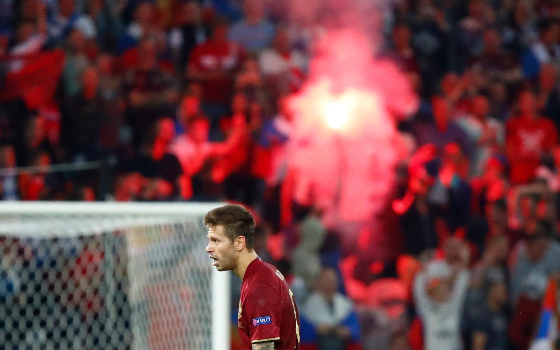 Russia's Fedor Smolov looks on as fans light a flare