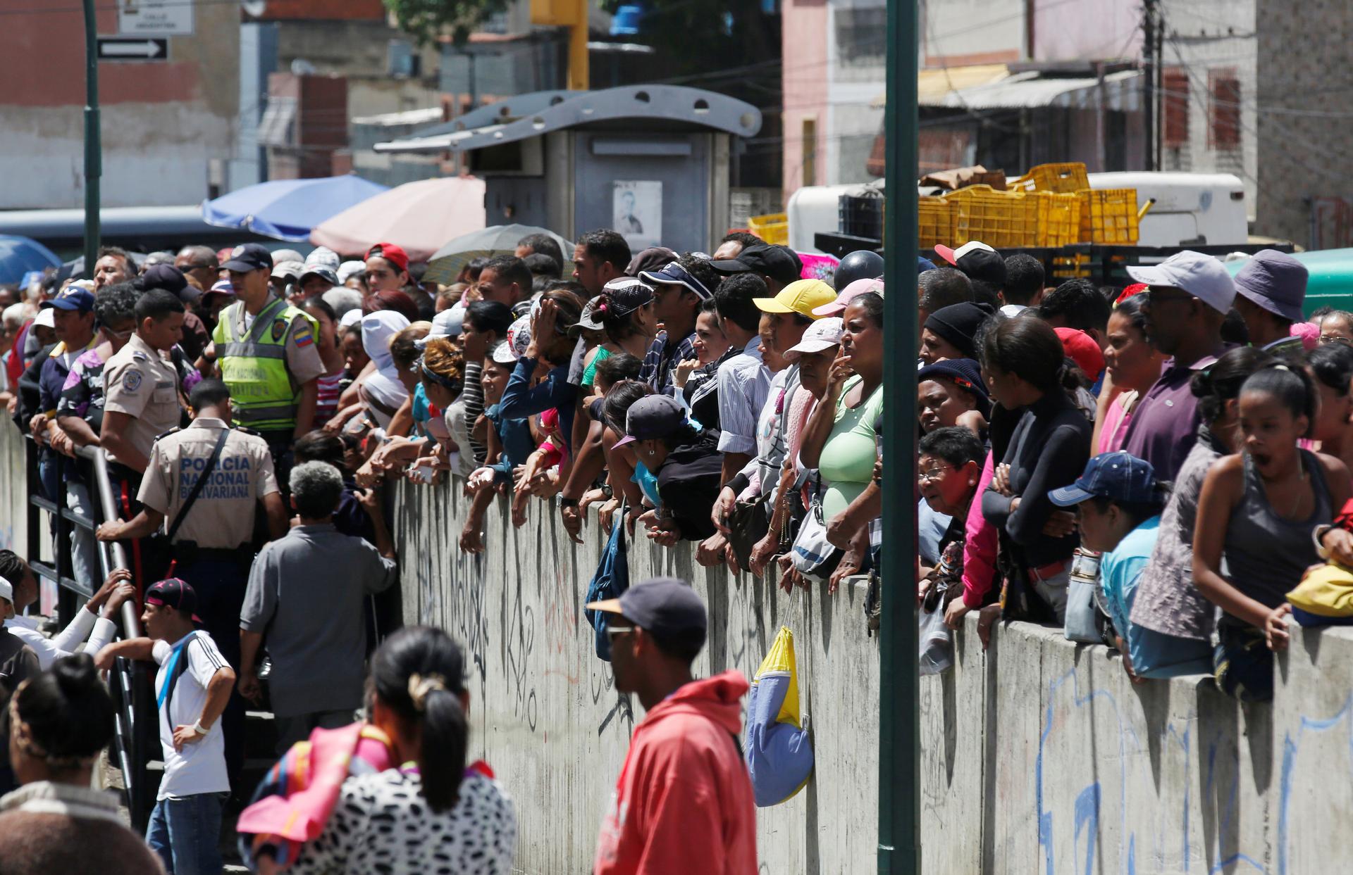 People gather to buy food and other staple goods outside a supermarket in Caracas, Venezuela June 30, 2016.