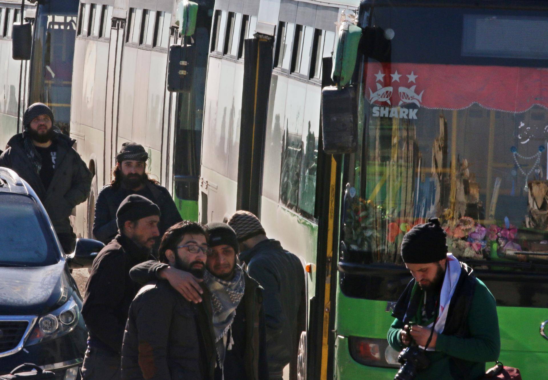 Men react as they stand outside buses evacuating people from a rebel-held sector of eastern Aleppo, Syria December 15, 2016.