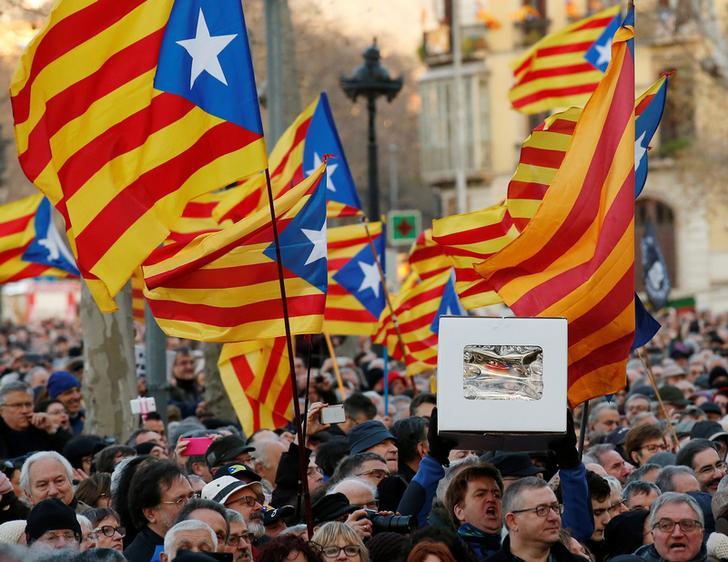 Protesters wave Catalan Estelada flags and hold up a faux ballot box as they await the arrival of former Catalan President Artur Mas outside court in Barcelona, Spain, Feb. 6.