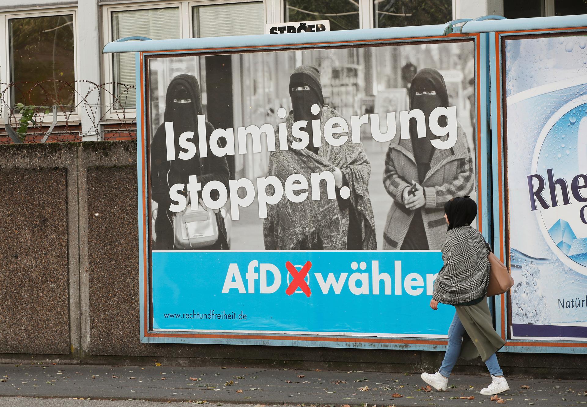 A woman walks past an AfD election campaign poster that reads, 