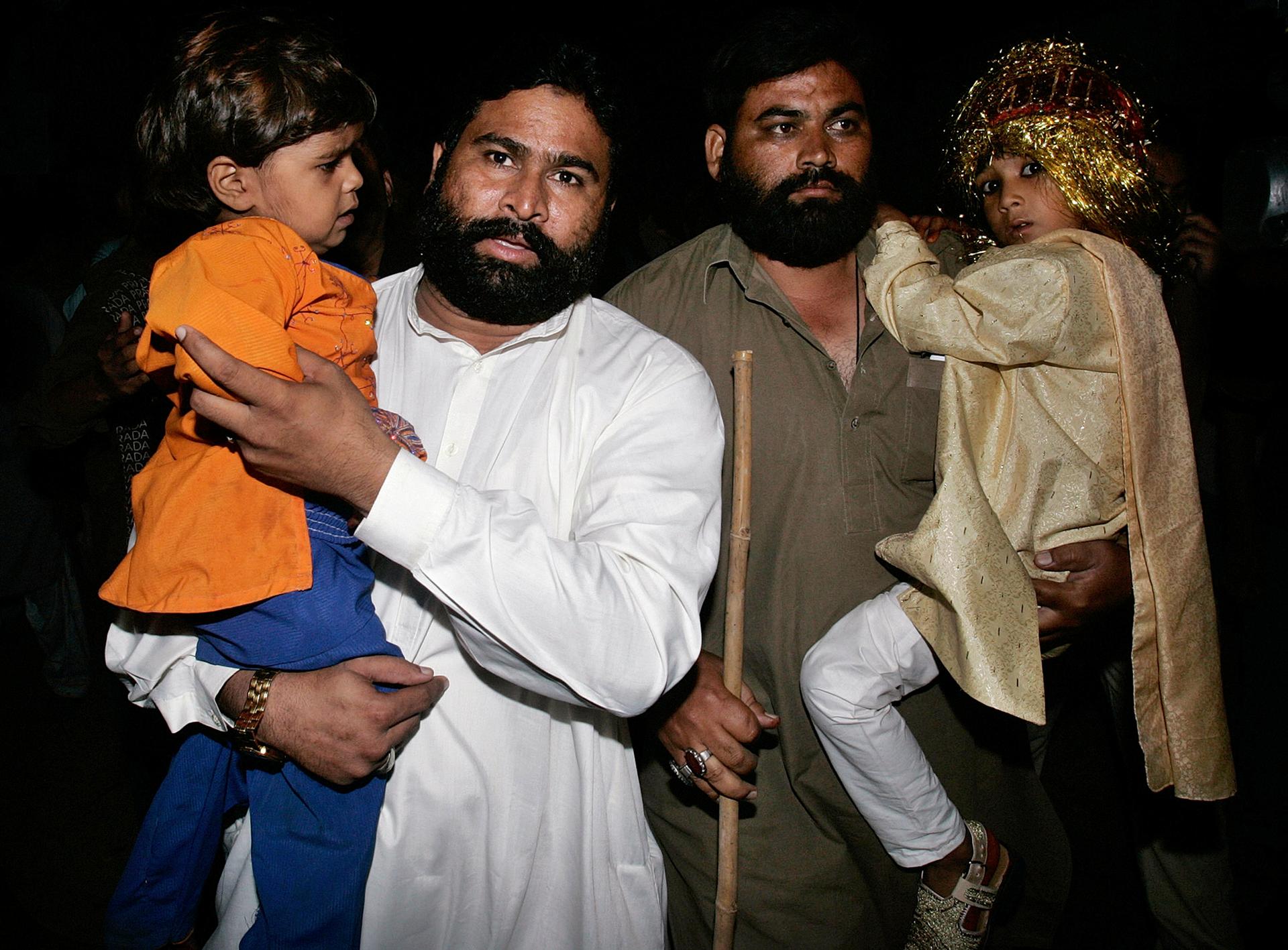 Seven-year-old groom Mohammad Waseem (R) and his 4-year-old bride Nisha (L) are escorted by security officials at a police station in Karachi after Pakistani police raided a child marriage ceremony and arrested a cleric who was presiding over the wedding,