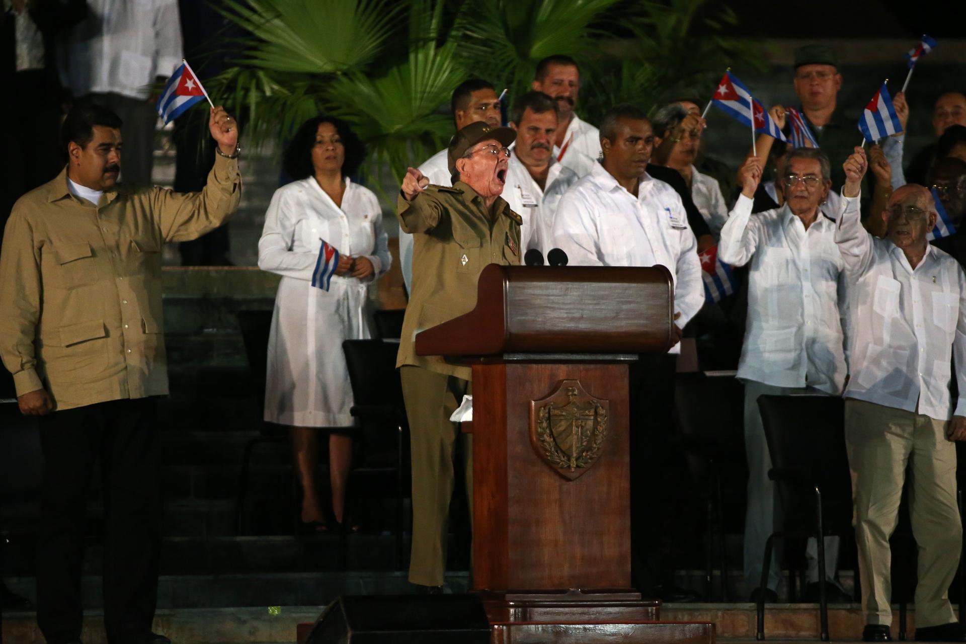 Venezuelan President Nicolas Maduro (L) waves a Cuban flag as Cuban President Raul Castro speaks during a tribute to former Cuban leader Fidel Castro in Santiago de Cuba.