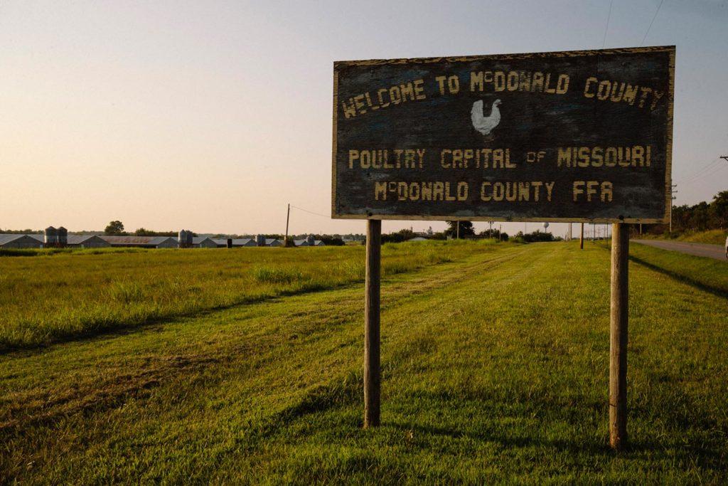 A county welcome sign stands near the Simmons Foods chicken processing plant in Southwest City, Missouri.