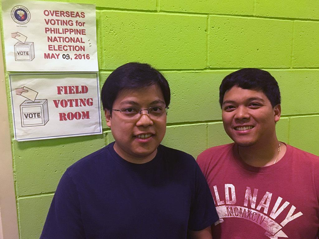 Brothers stand in front of polling place signs, against green wall