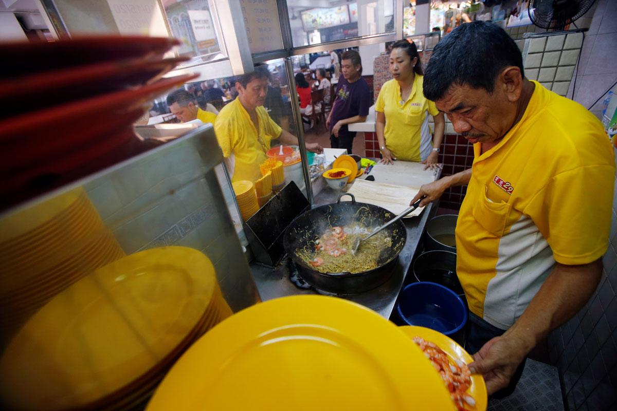 Hawker Alex See, 66, and his daughter Penny See, 33, cooking at their Geylang Lorong 29 Fried Hokkien Mee stall.