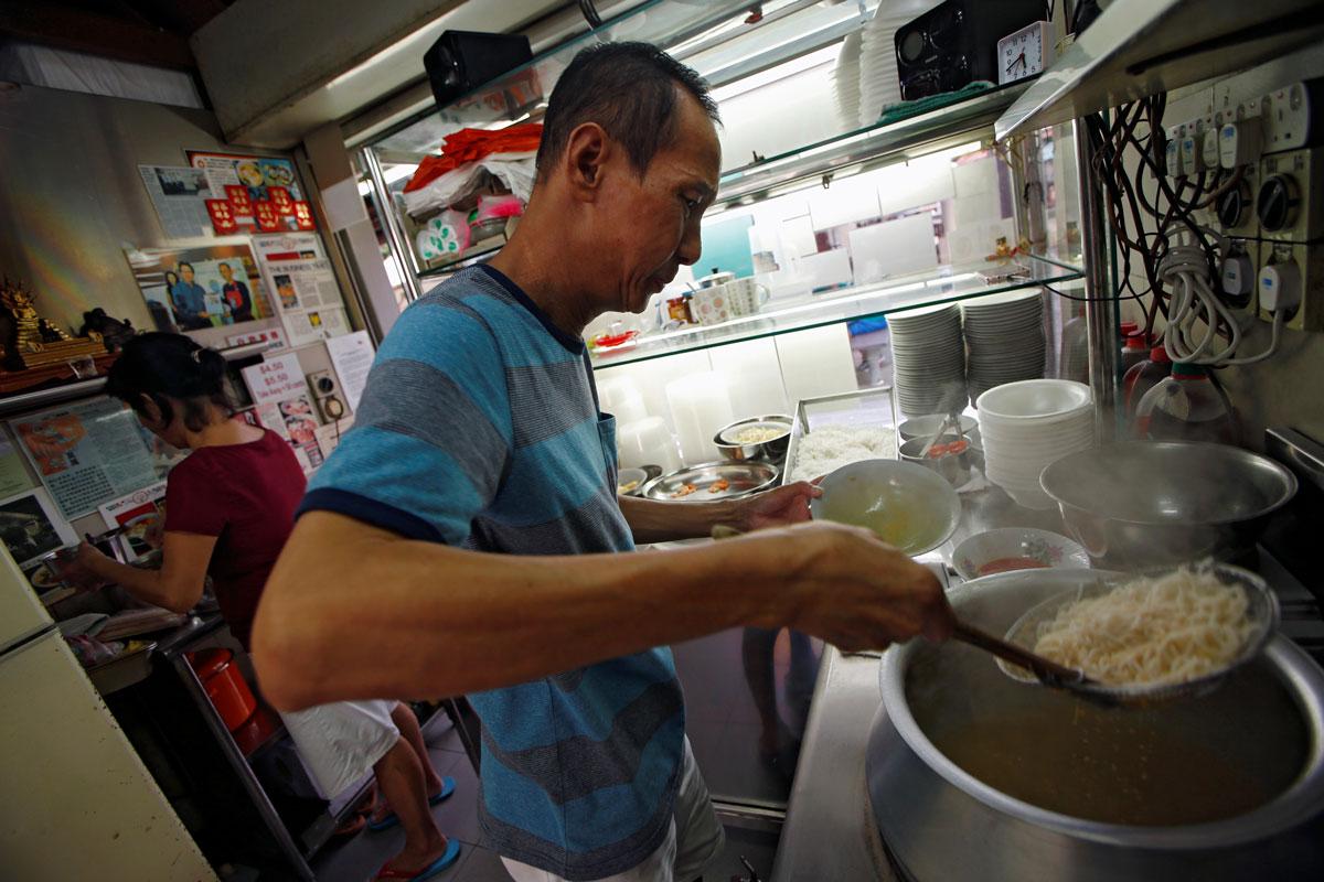 Hawker Lim Swee Heng prepares a bowl of laksa noodles.