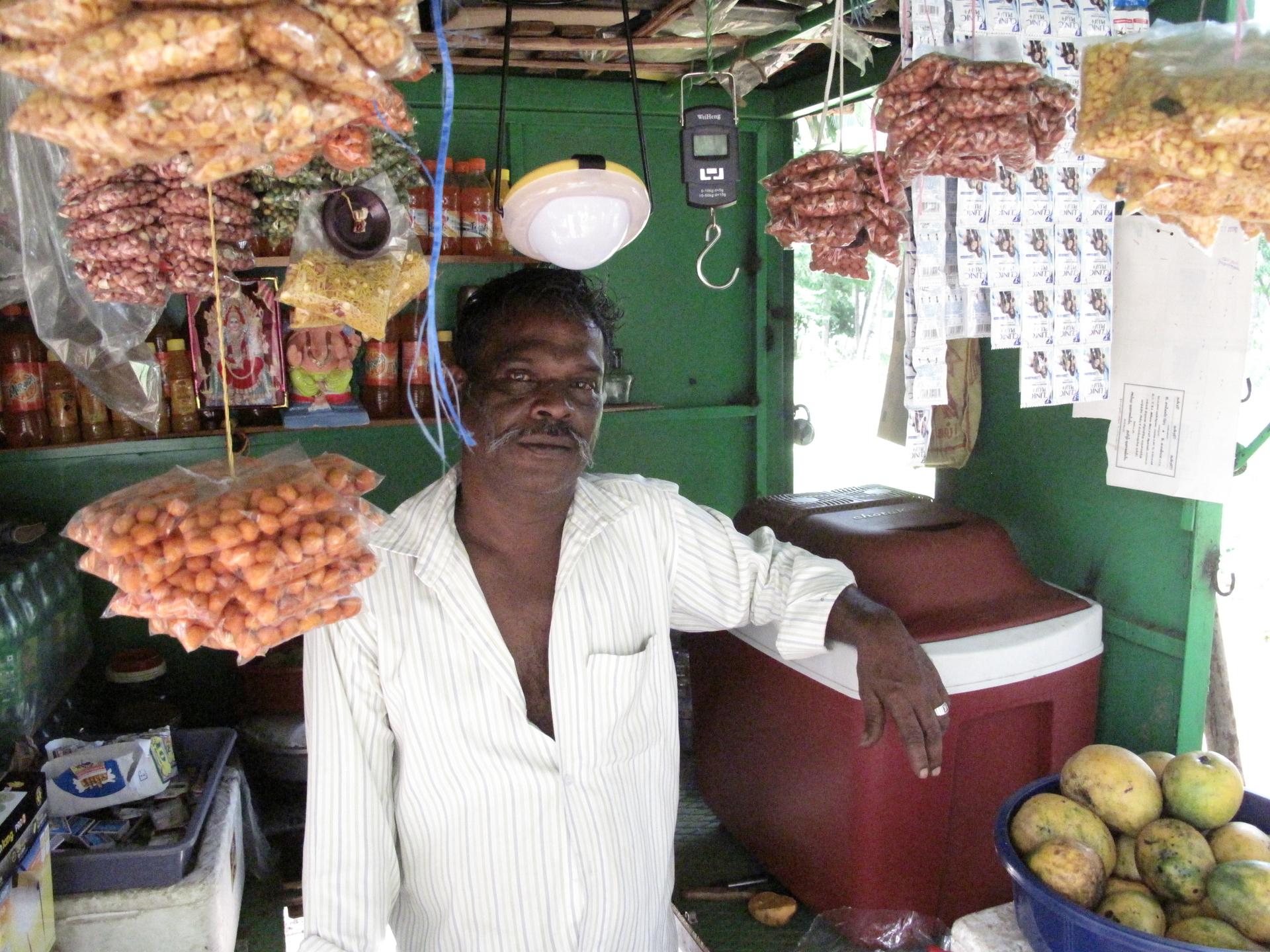 Sinhappan owns a small shop on the side of a highway in Tamil Nadu. The lamp above his head is one of Essmart’s solar lamps. He’s resting his arm on another one of Essmart’s products: A low-power refrigerator, which he uses to keep his beverages cold all