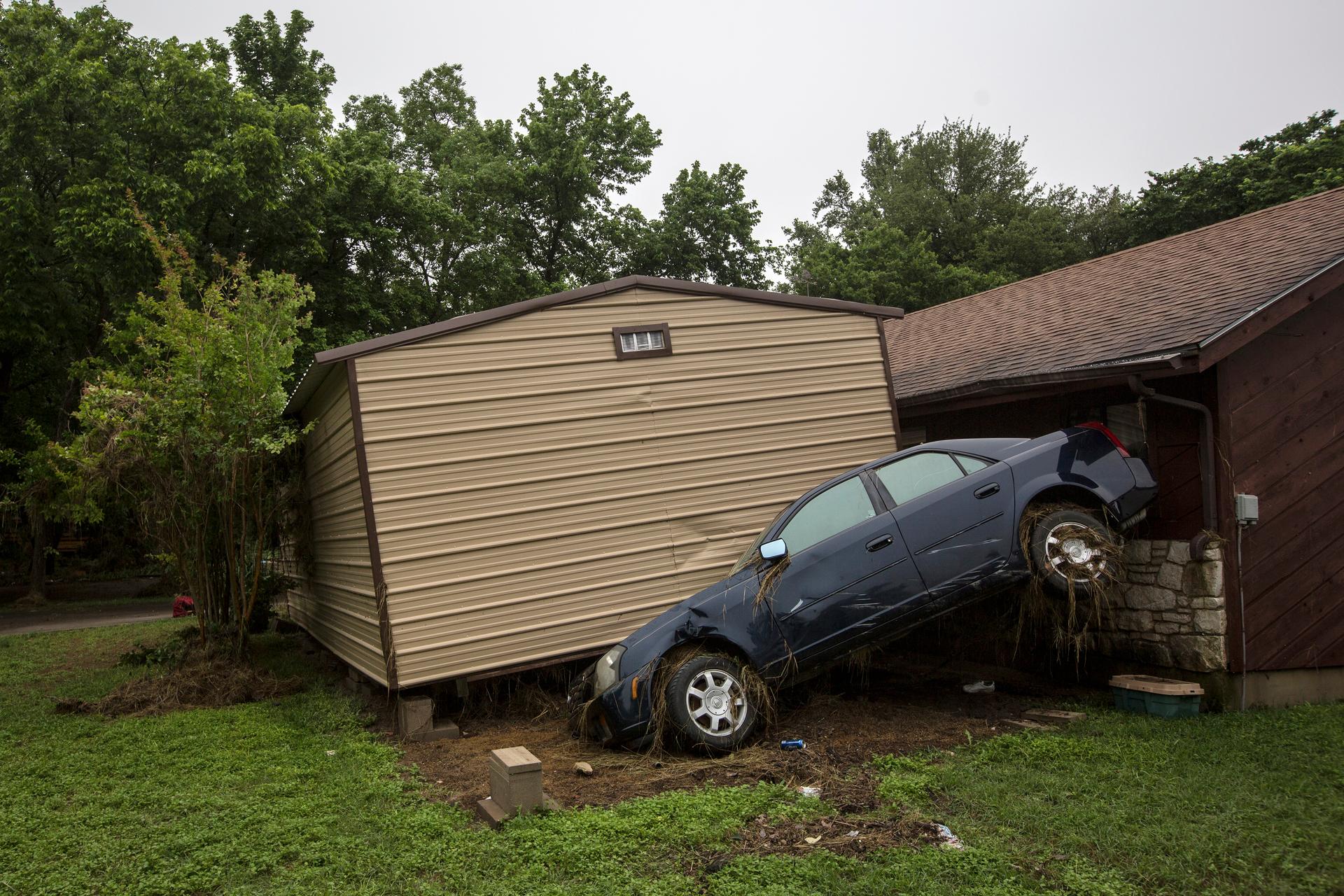 Flood damaged vehicles and debris are strewn across lawns in San Marcos, Texas May 26, 2015.
