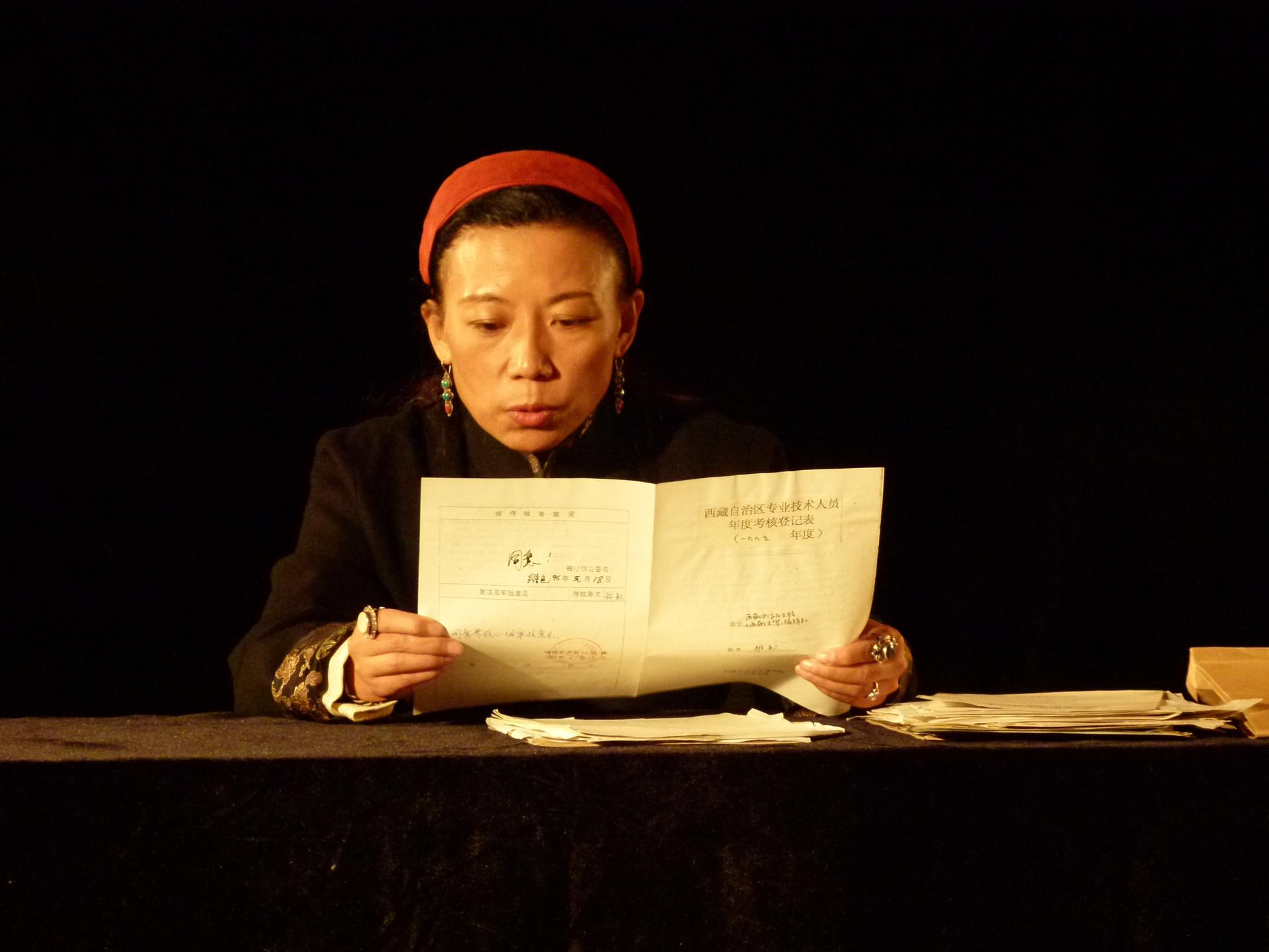 Tibetan writer Tsering Woeser reads from a government document about her activities in Zhu Rikun's film, 