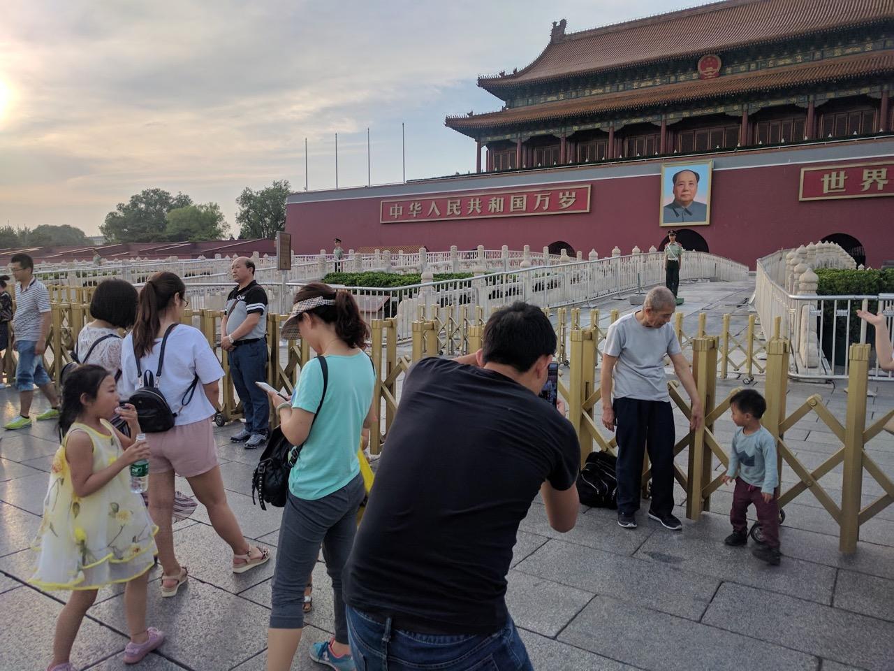 Chinese pose for photos near Mao Zedong's photo at the entrance to the Forbidden City in Tiananmen Square, Beijing