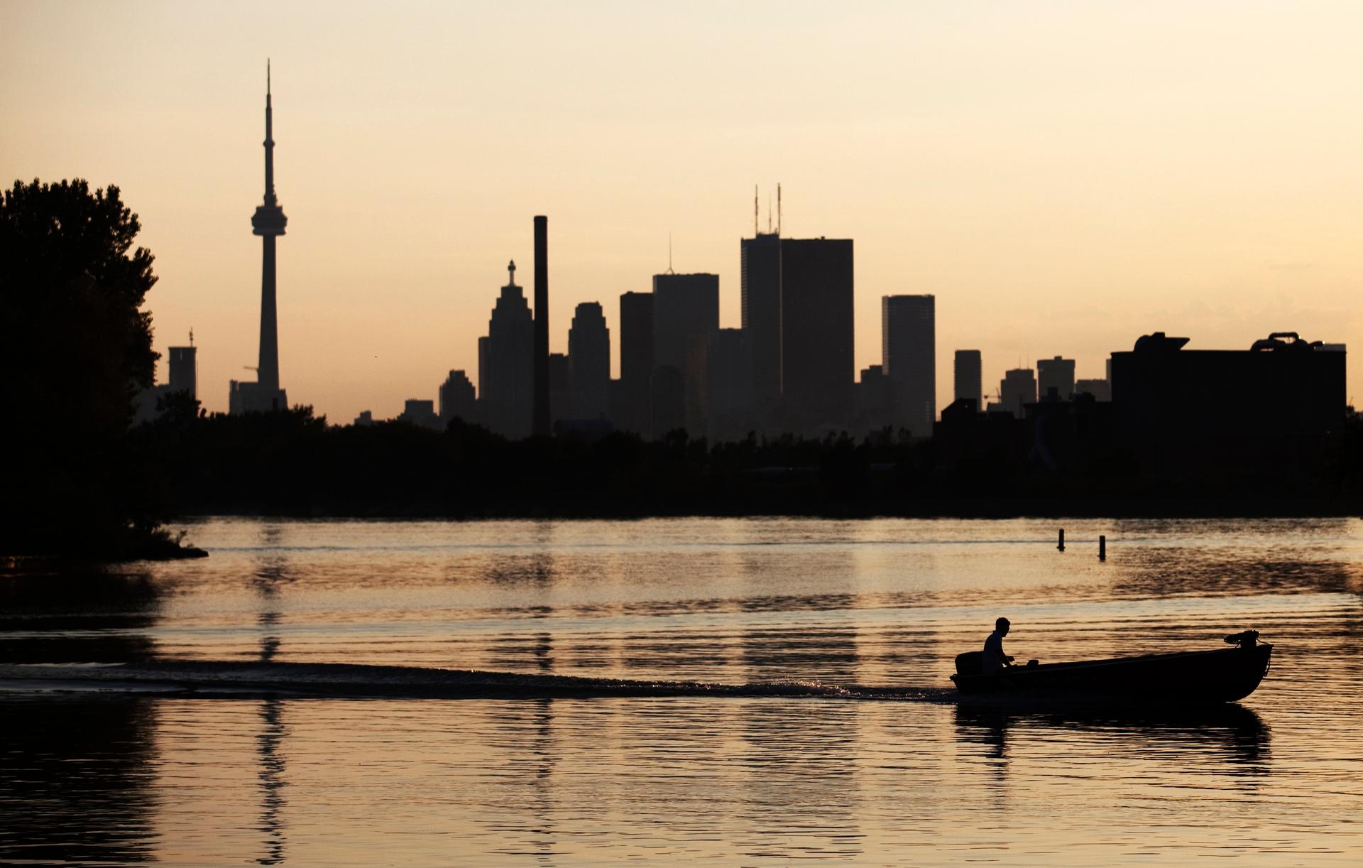 A boat passes through in front of the Toronto skyline during sunset at Ashbridge's Bay Park.