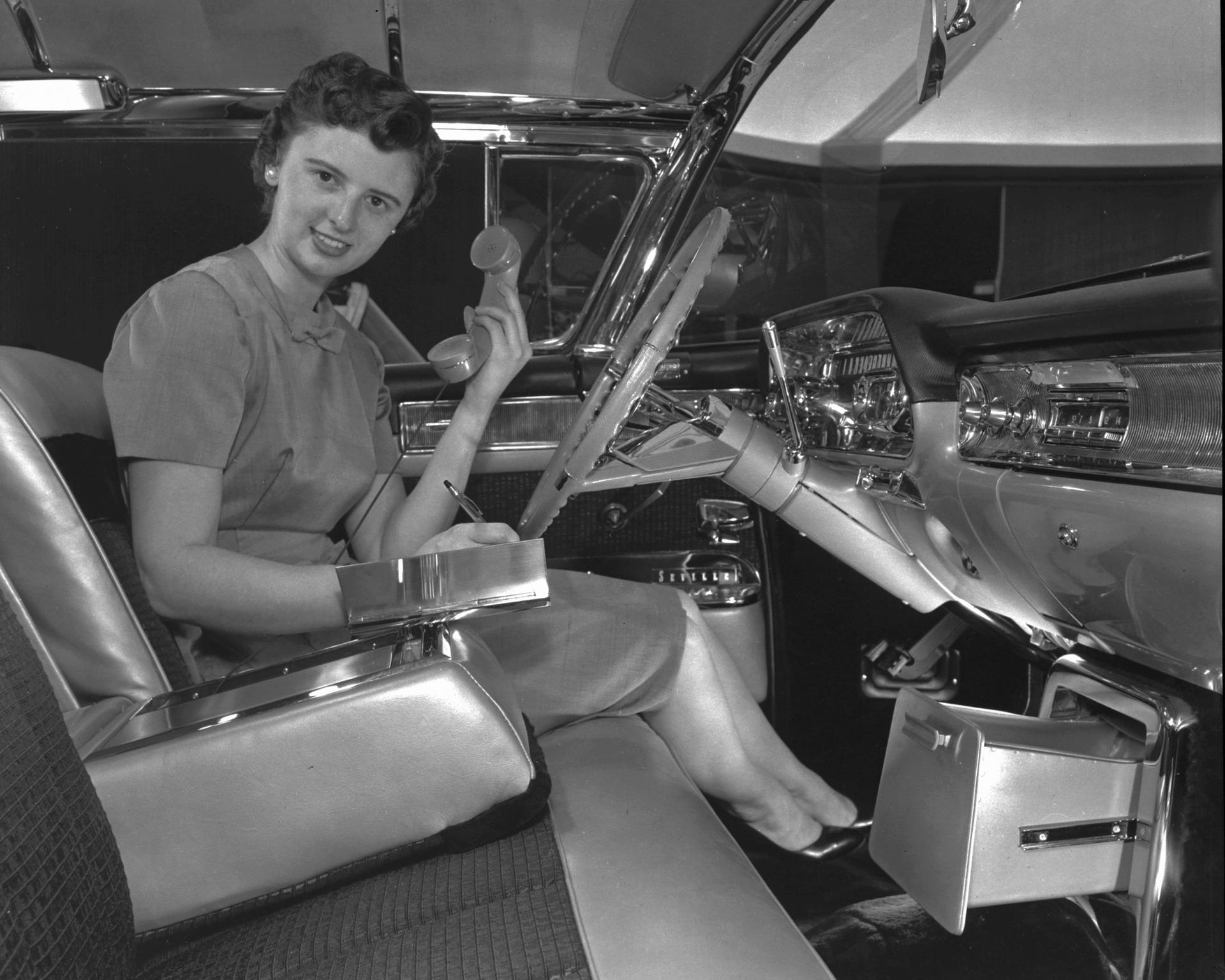 Suzanne Vanderbilt demonstrating an early car phone and built-in memo pad — custom features for her 1958 exhibition-model Cadillac Eldorado Seville.