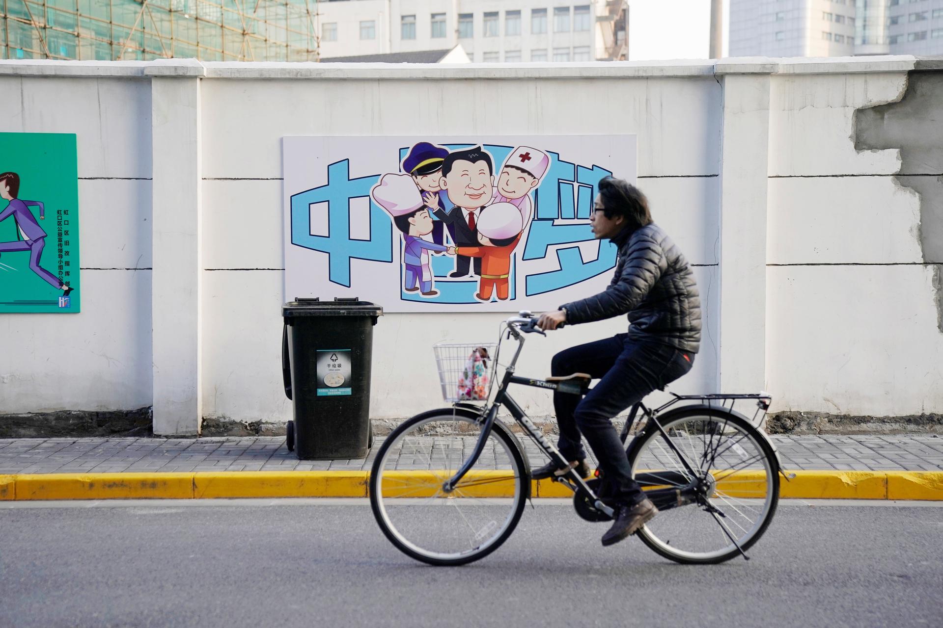 A cartoon depicting Chinese President Xi Jinping with the Chinese characters reading "Dream of China" is seen in the background as a bicyclist rides past.