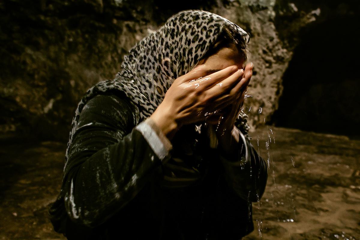 Turkia Hussein washes her face with sacred waters of the fountain. She is Yazidi again.