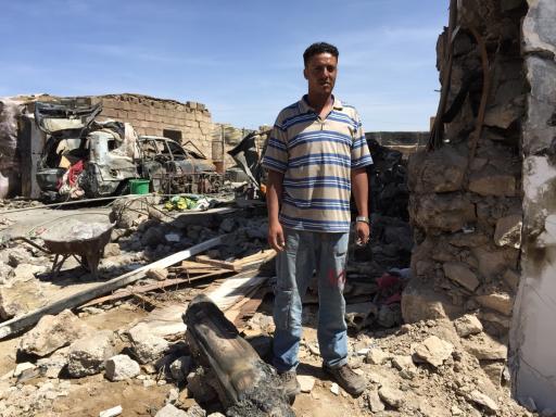 Ayman al-Sanabani stands outside the wreckage of his family's home.