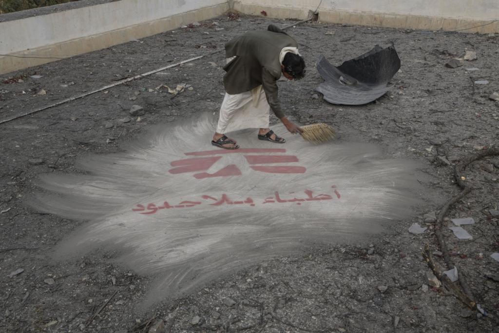 A hospital guard sweeps away debris from an airstrike. The roof of the hospital had been painted with the logo of Doctors Without Borders so that jets conducting airstrikes would know this facility was being run by the international aid organization.