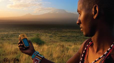 Lion Guardian Ng’ida takes a GPS point in front of Mt. Kilimanjaro. GPS data helps Lion Guardians track animals and keep livestock out of harm’s way.