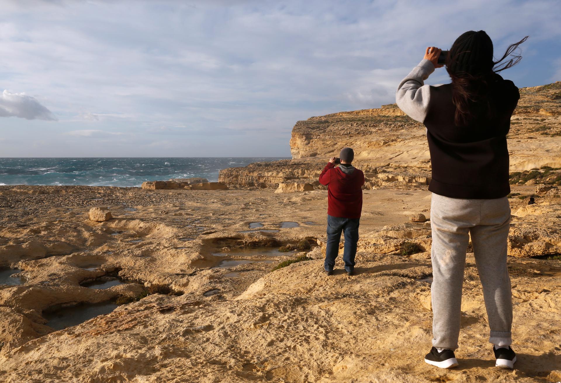 People take pictures of the site where the natural structure known as the Azure Window collapsed