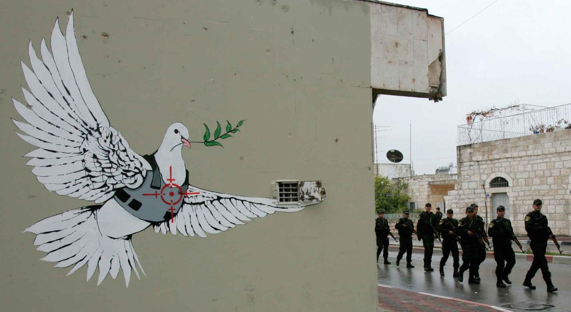 Members of the Palestinian security forces patrol near a mural by graffiti artist Banksy during a visit by then US President George W. Bush to the West Bank town of Bethlehem January 10, 2008.