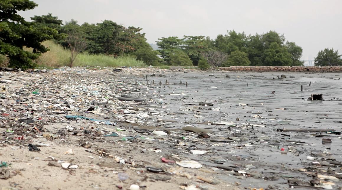 The shoreline along Guarabana Bay, near Rio de Janeiro, is littered with debris and trash. The water in the bay itself is murky brown due to oils spills and other pollutants, activists say.