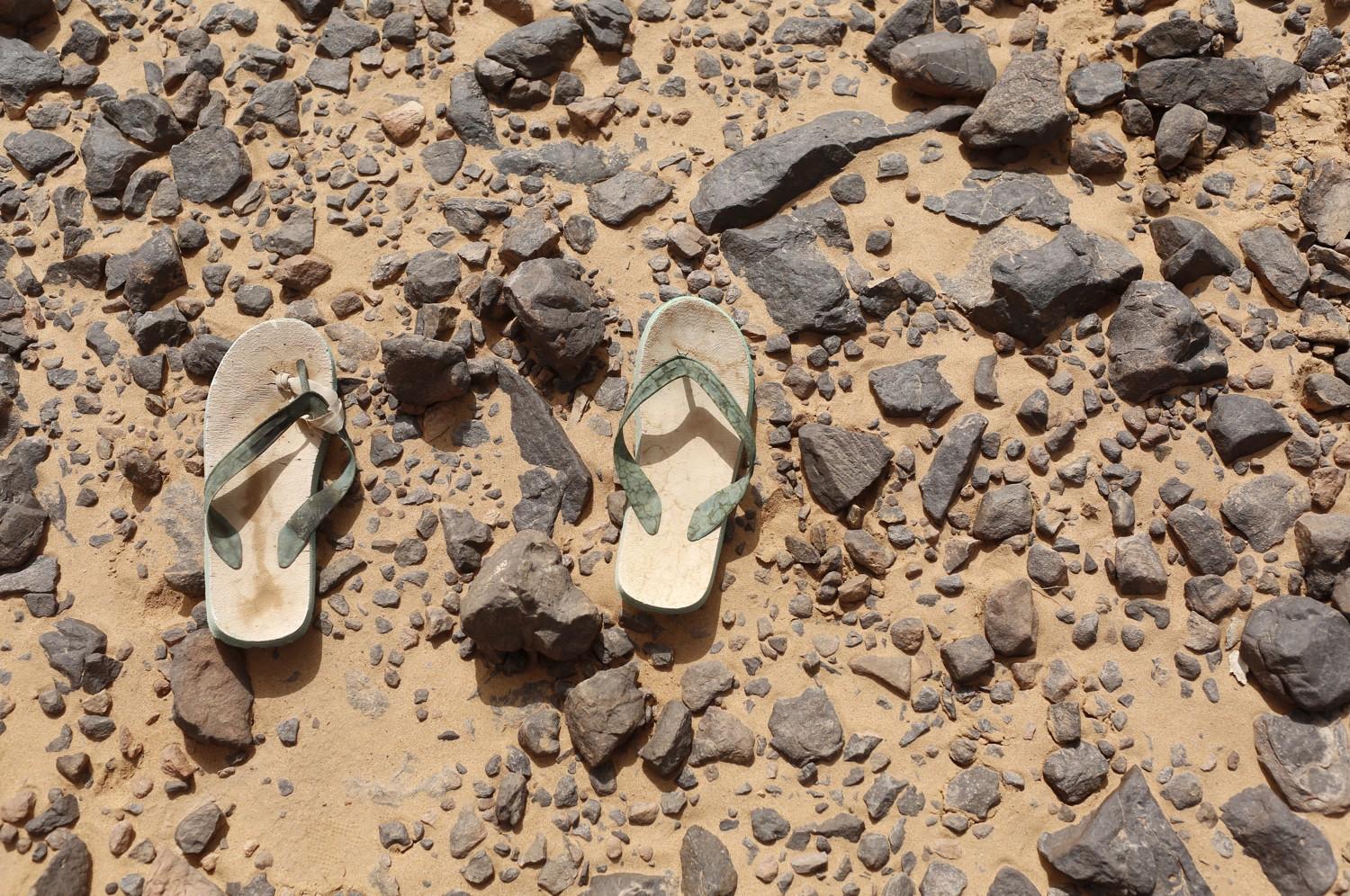 A pair of flip flops, left behind by a migrant, lies on the ground in the Sahara Desert near the border of Algeria and Libya.