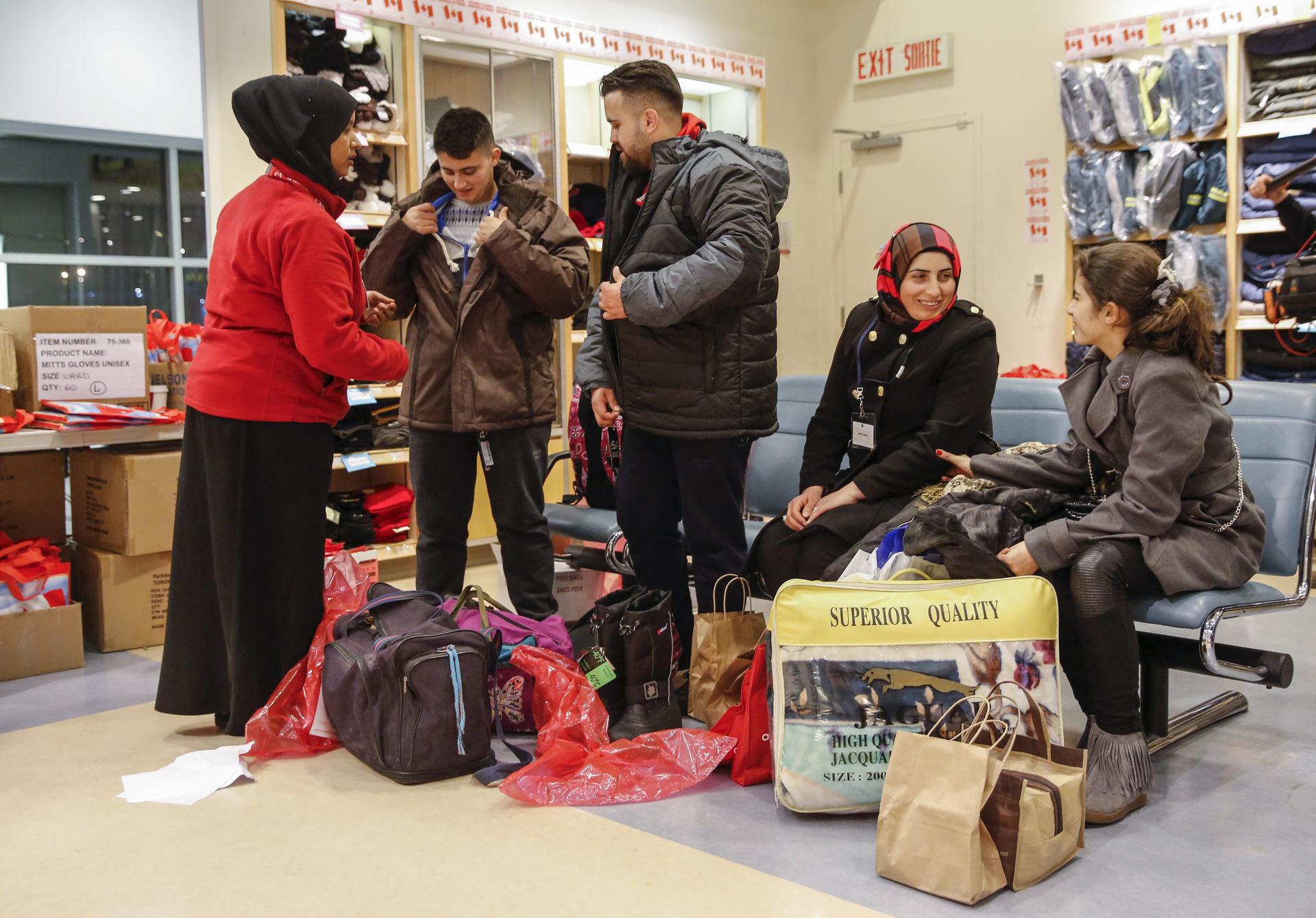 Syrian refugees receive winter clothing as they arrive at the Pearson Toronto International Airport in Mississauga, Ontario, December 18, 2015.