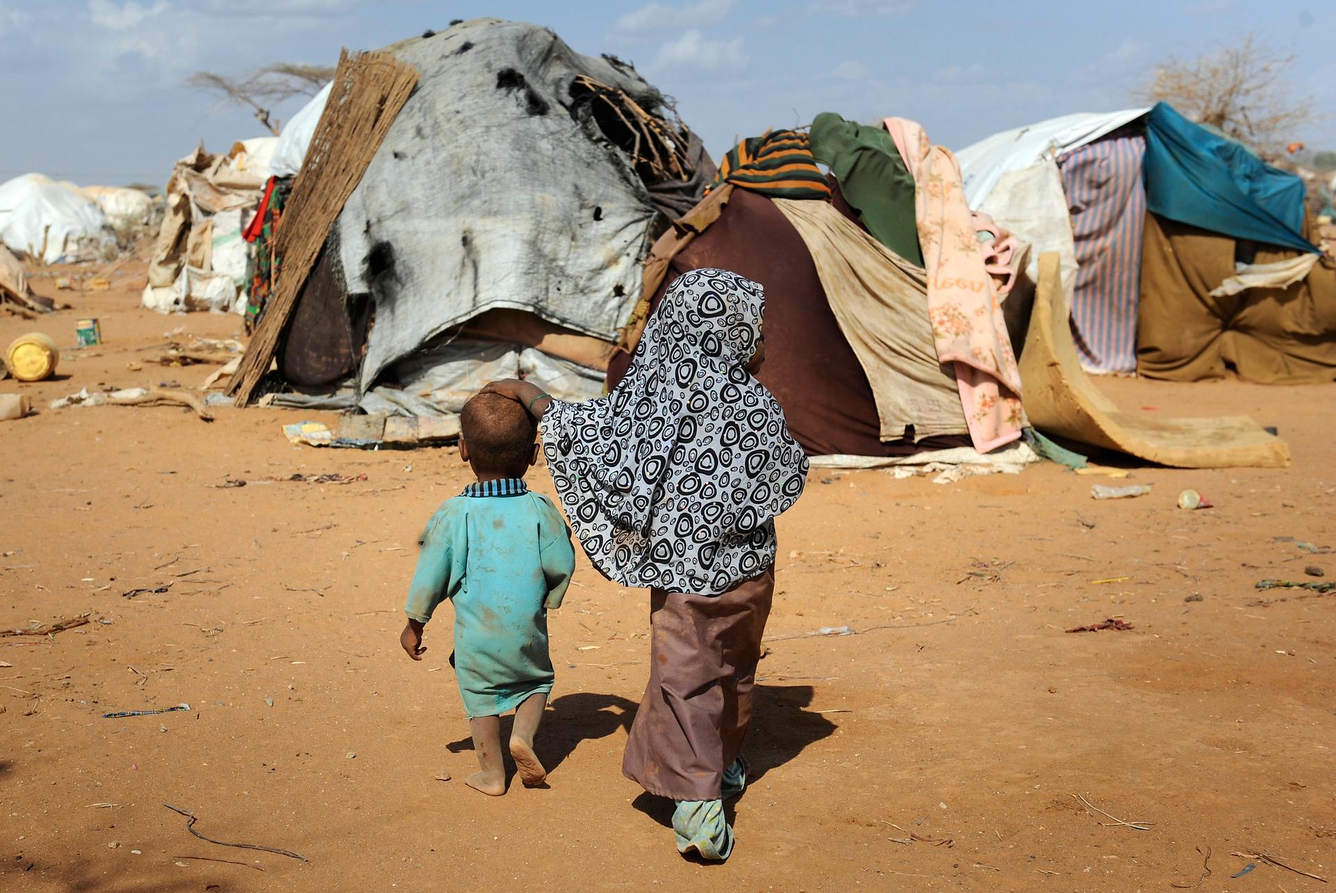 Children walk together among makeshift homes, or 