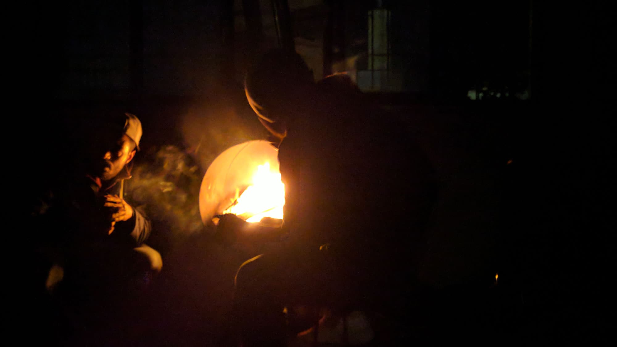 Yassin, 24, from Algeria, has been stuck on Lesbos for one year now. At night, he and the others who live here gather in front of a fire lit in a metal barrel.