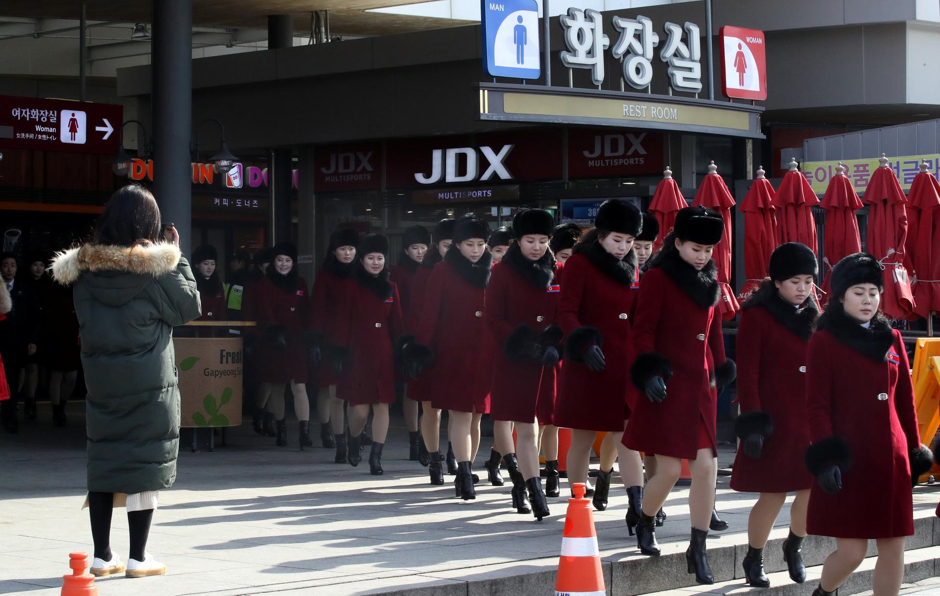 Members of North Korean cheering squad, dressed in red knee length jackets with black fur trim, walk at an expressway service area in Gapyeong, South Korea, Feb. 7, 2018.