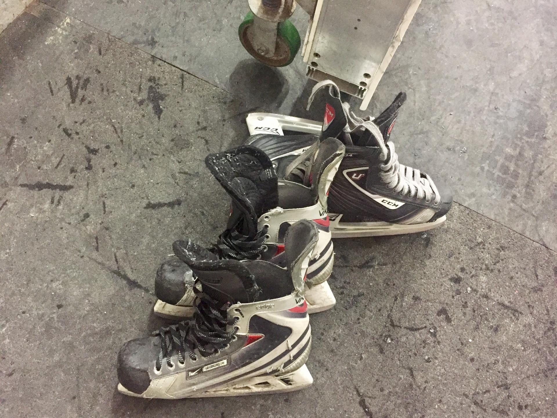 Close up of hockey skates on the floor.