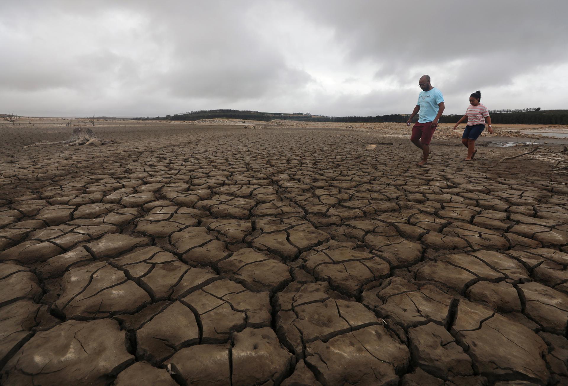 A family negotiates their way through caked mud around a dried up section of the Theewaterskloof dam near Cape Town.