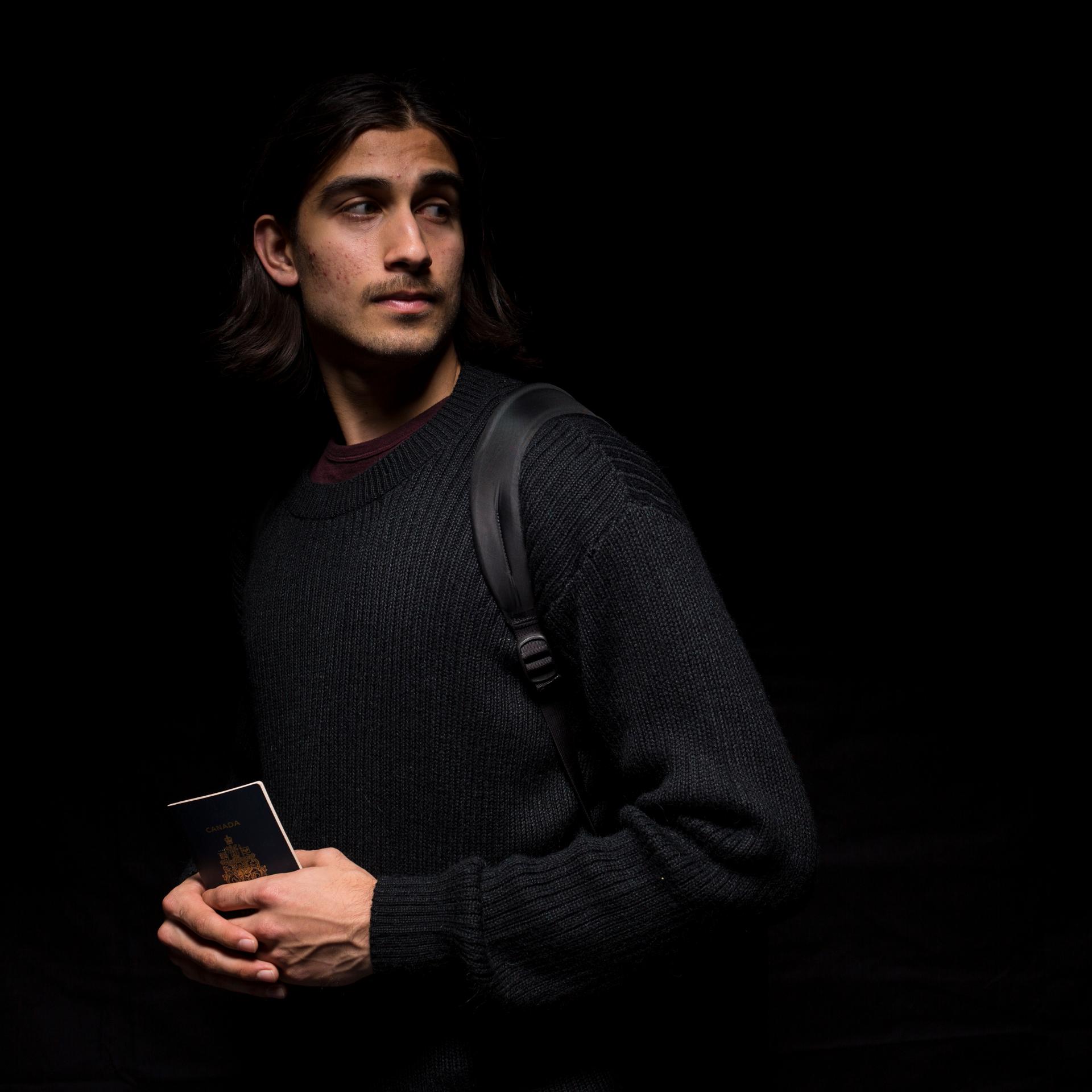 Young man with backpack and tablet, against a black background