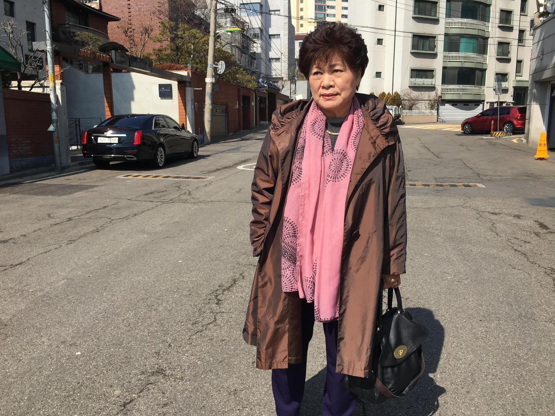 Portrait of Sue Kinsler, a Christian missionary who helps North Korean disabilities, wearing a brown jacket and pink scarf.
