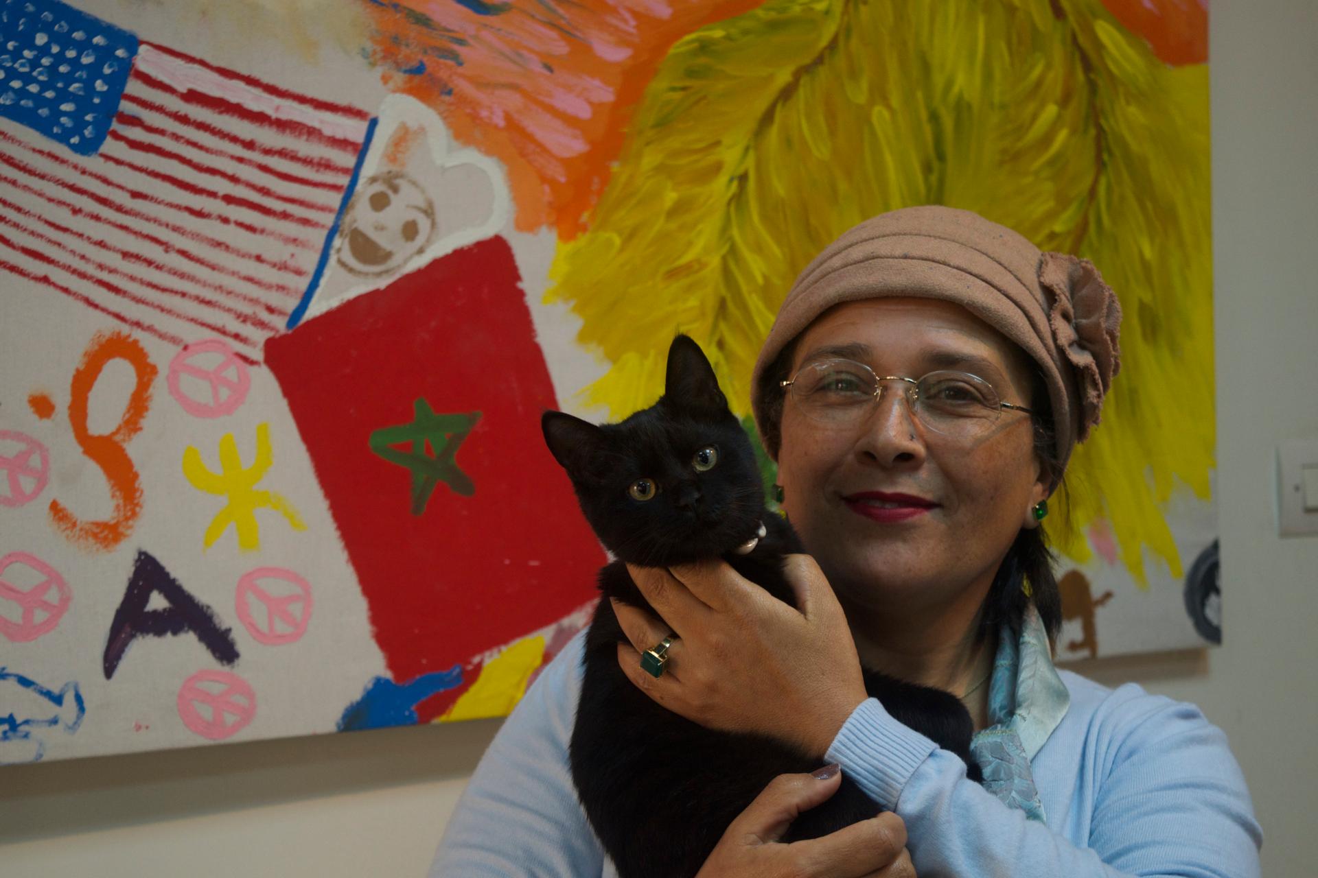 Jamila Bargach and he cute cat in front of a mural