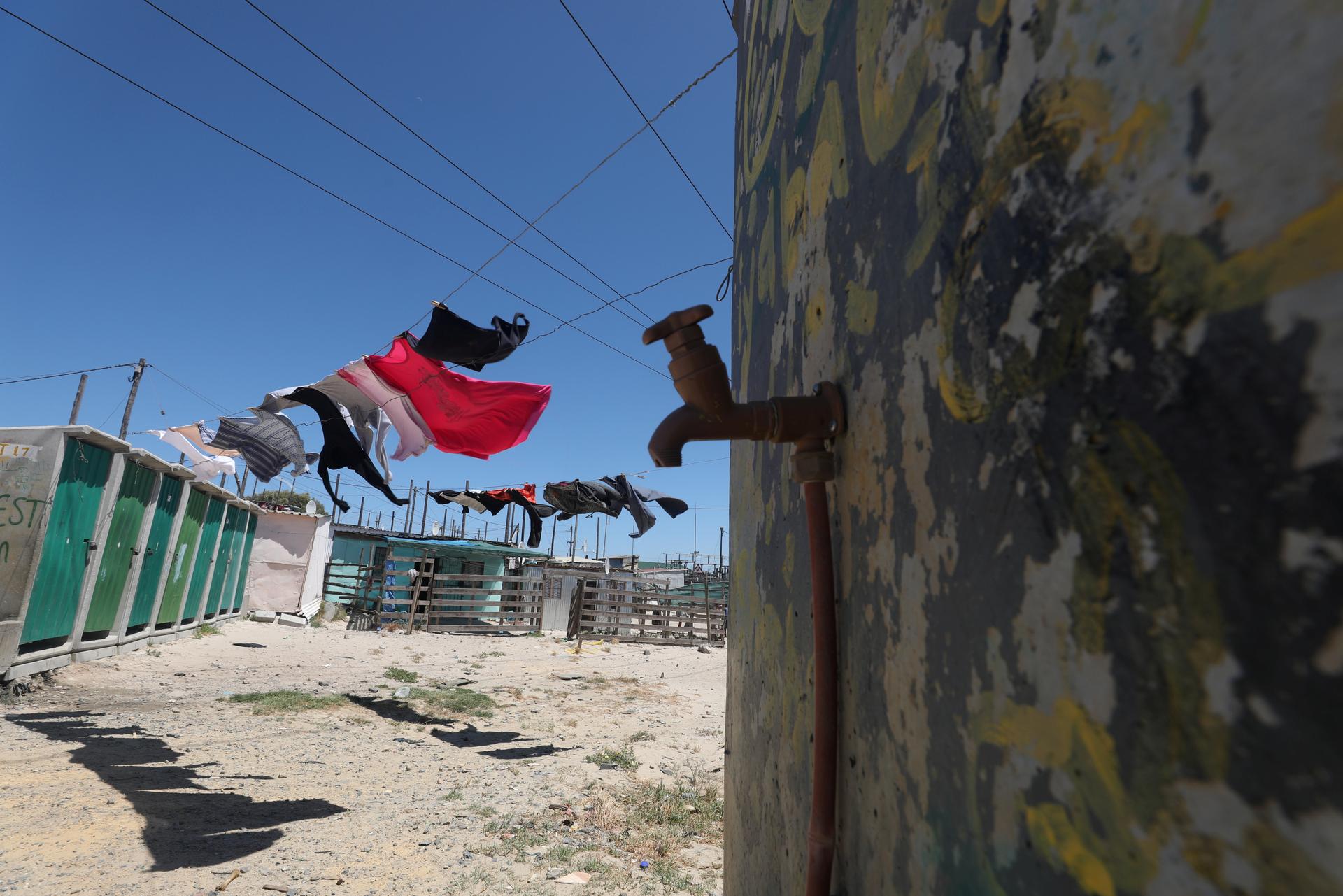 Clothing hangs above a communal tap in Khayelitsha township, near Cape Town,