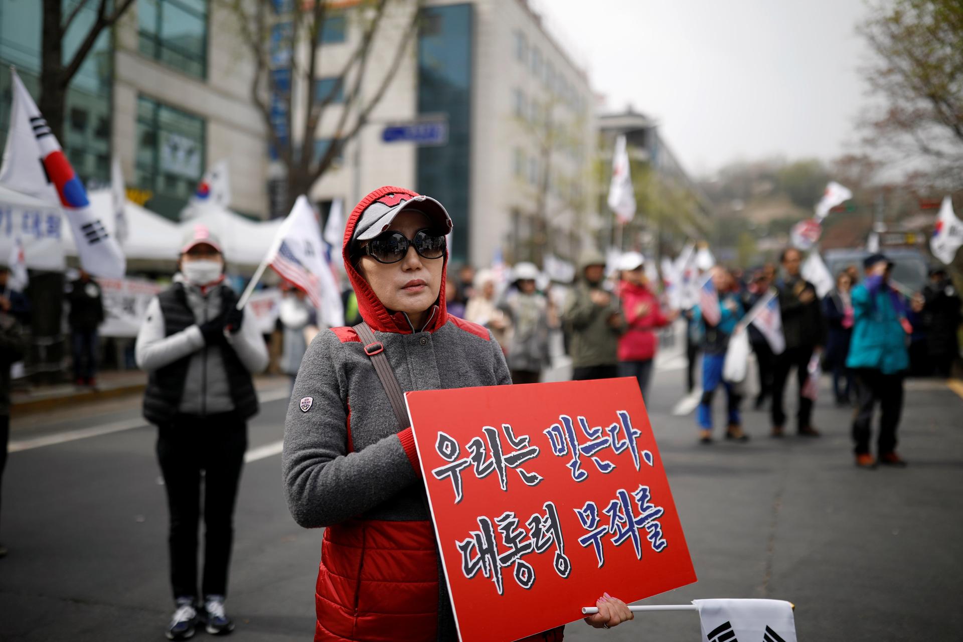 Members of a conservative civic group carry South Korean flags and placards in a street protest to support ousted President Park Geun-hye.