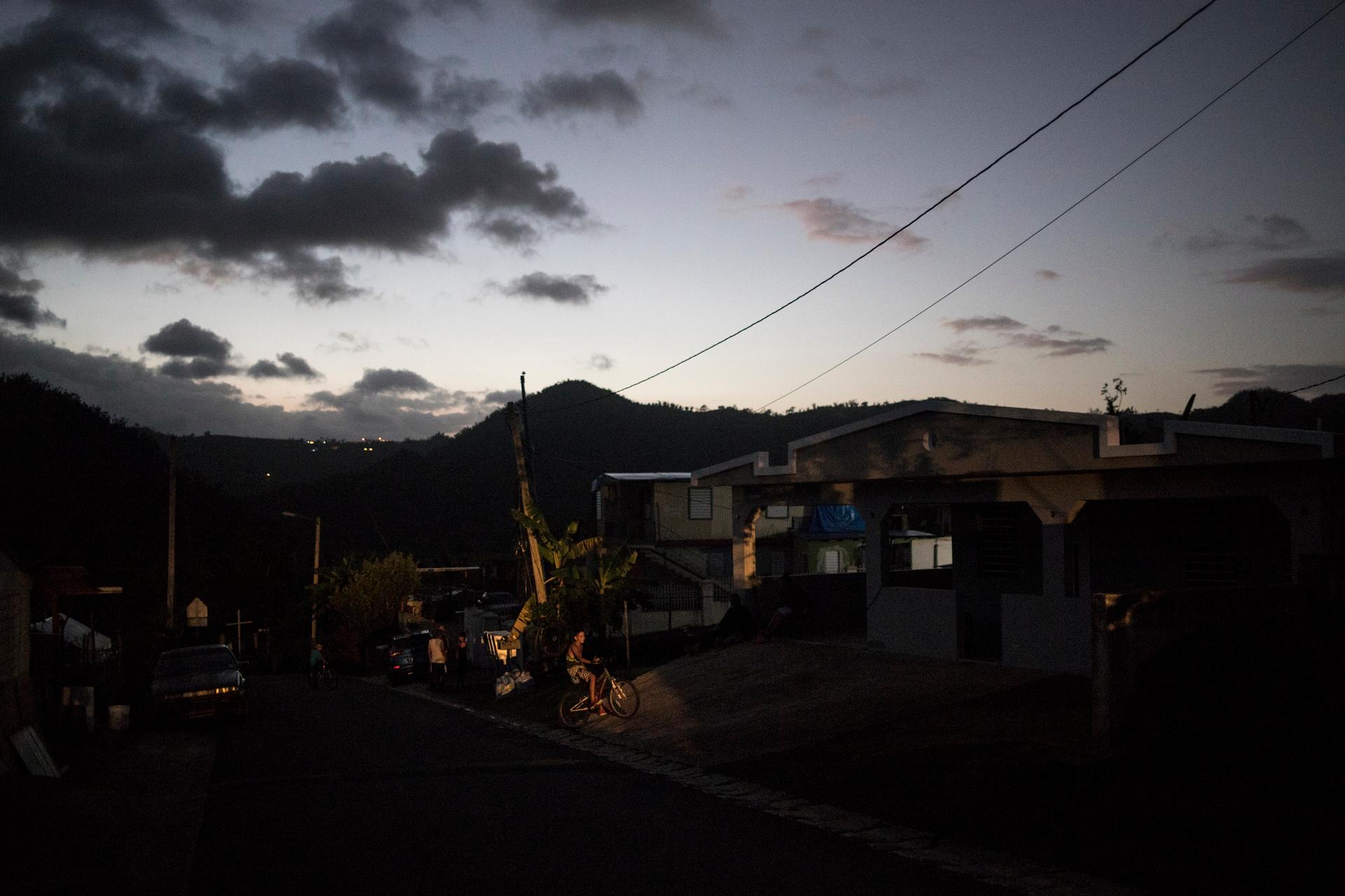 Car headlights illuminate a boy on his bike in the town of Utuado