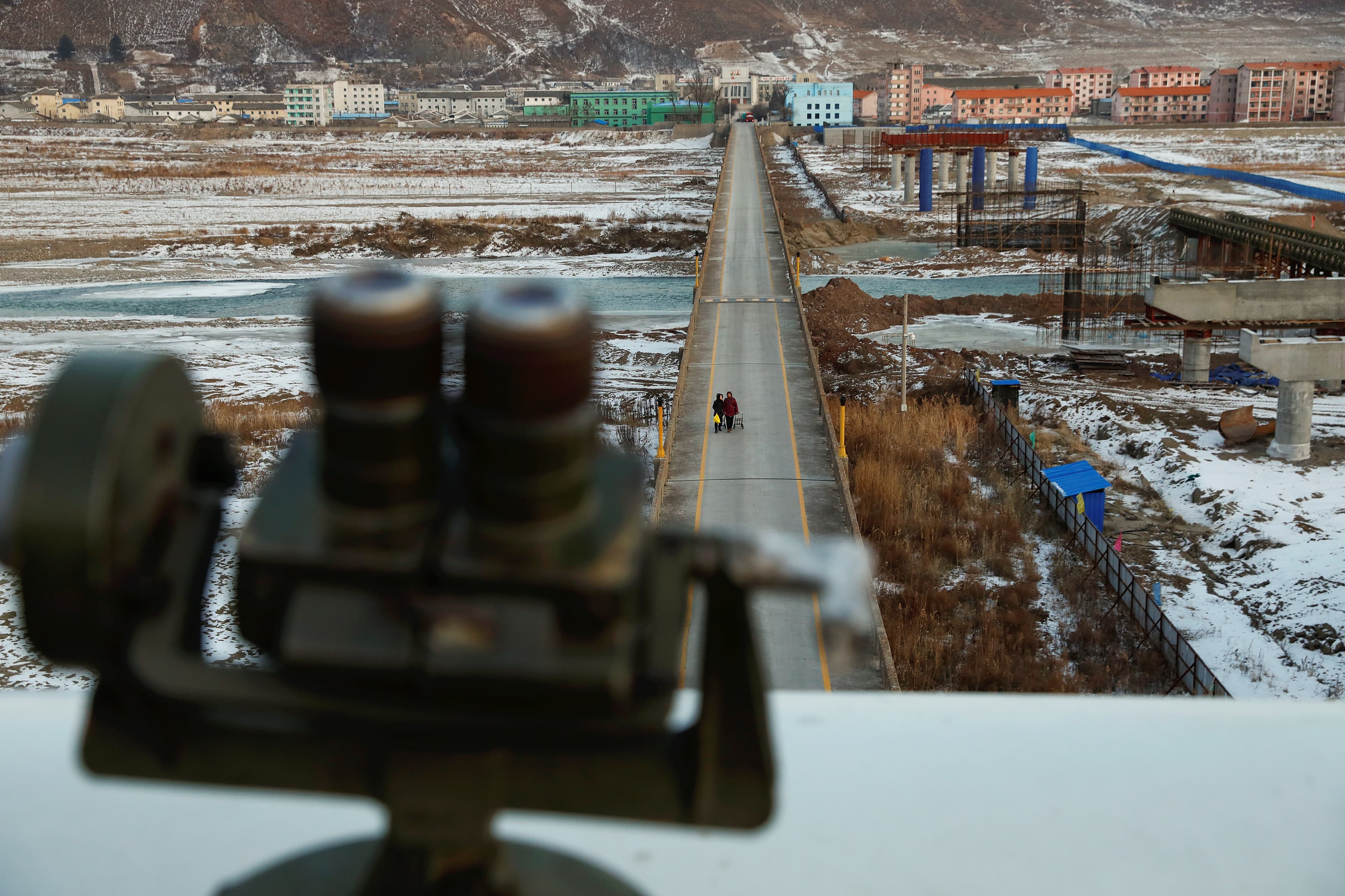Women, photographed from the Chinese side of border, are seen from a viewing point used by tourists to look into North Korea,