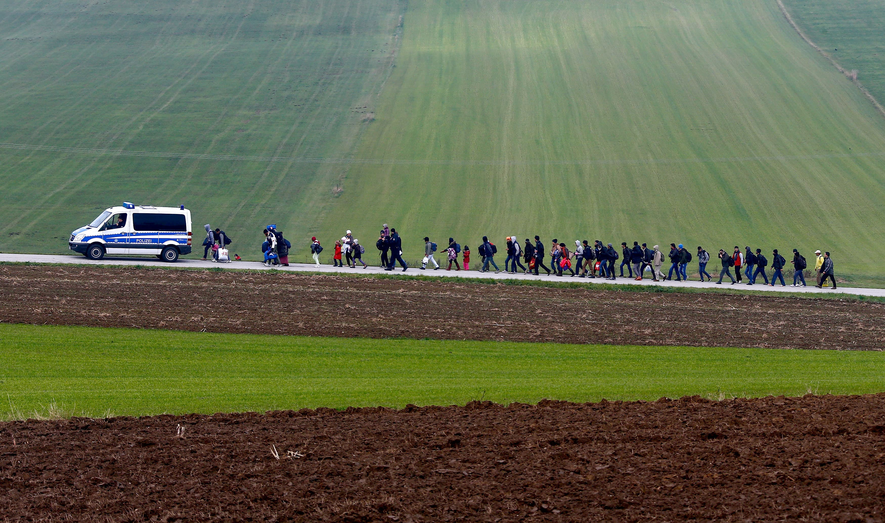 German police escort migrants to a registration center after they crossed the Austrian-German border in Wegscheid near Passau, Germany, Oct. 20, 2015.