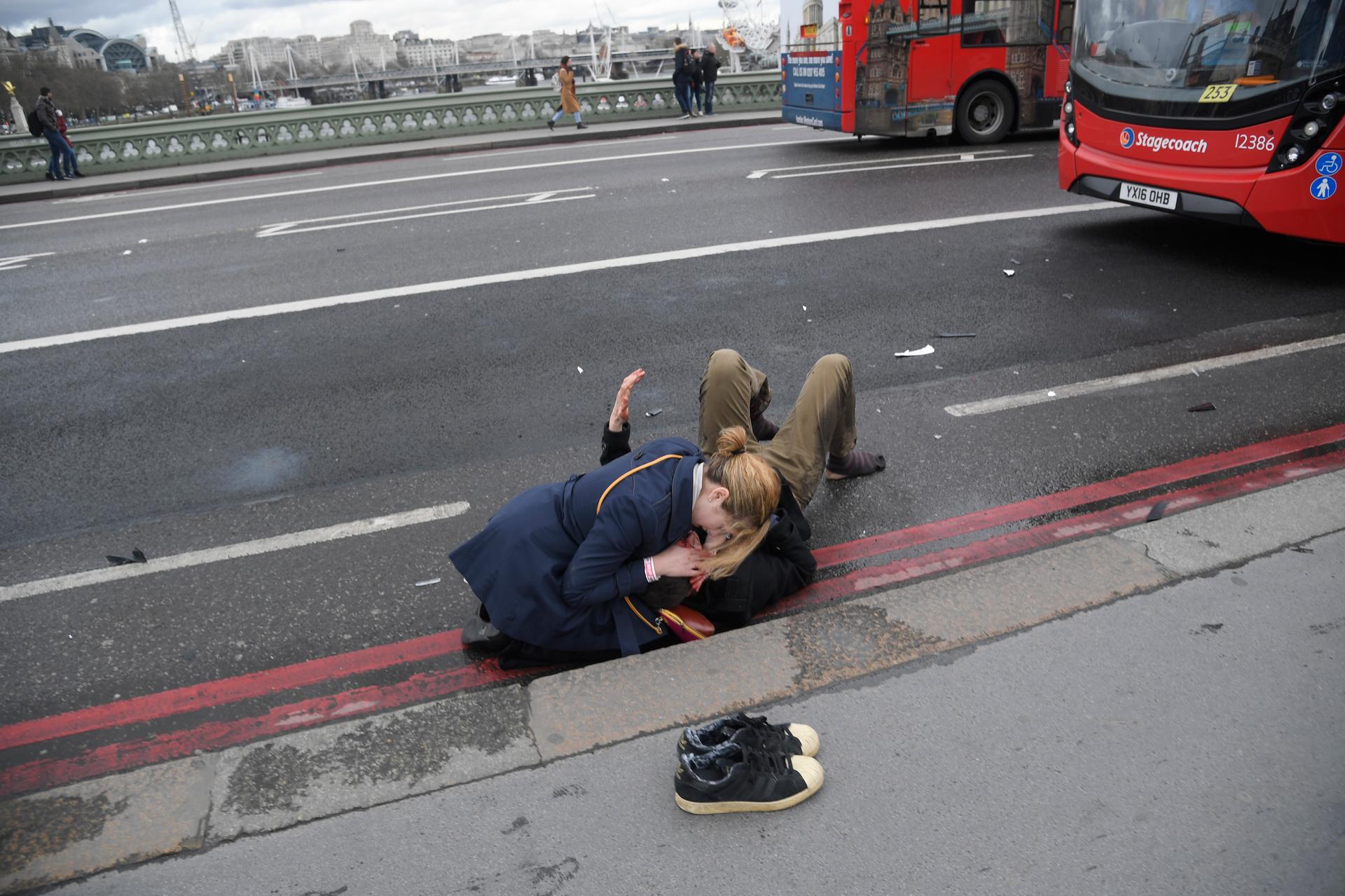 A woman assists an injured person after an incident on Westminster Bridge in London.