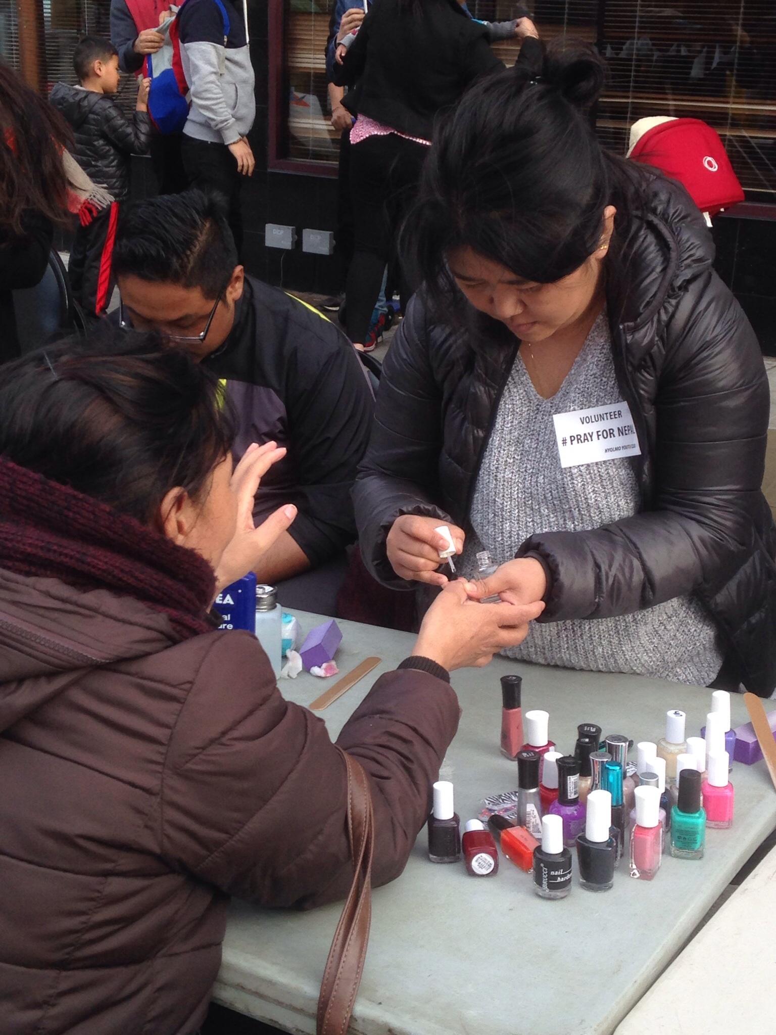 Women paint nails to raise money.