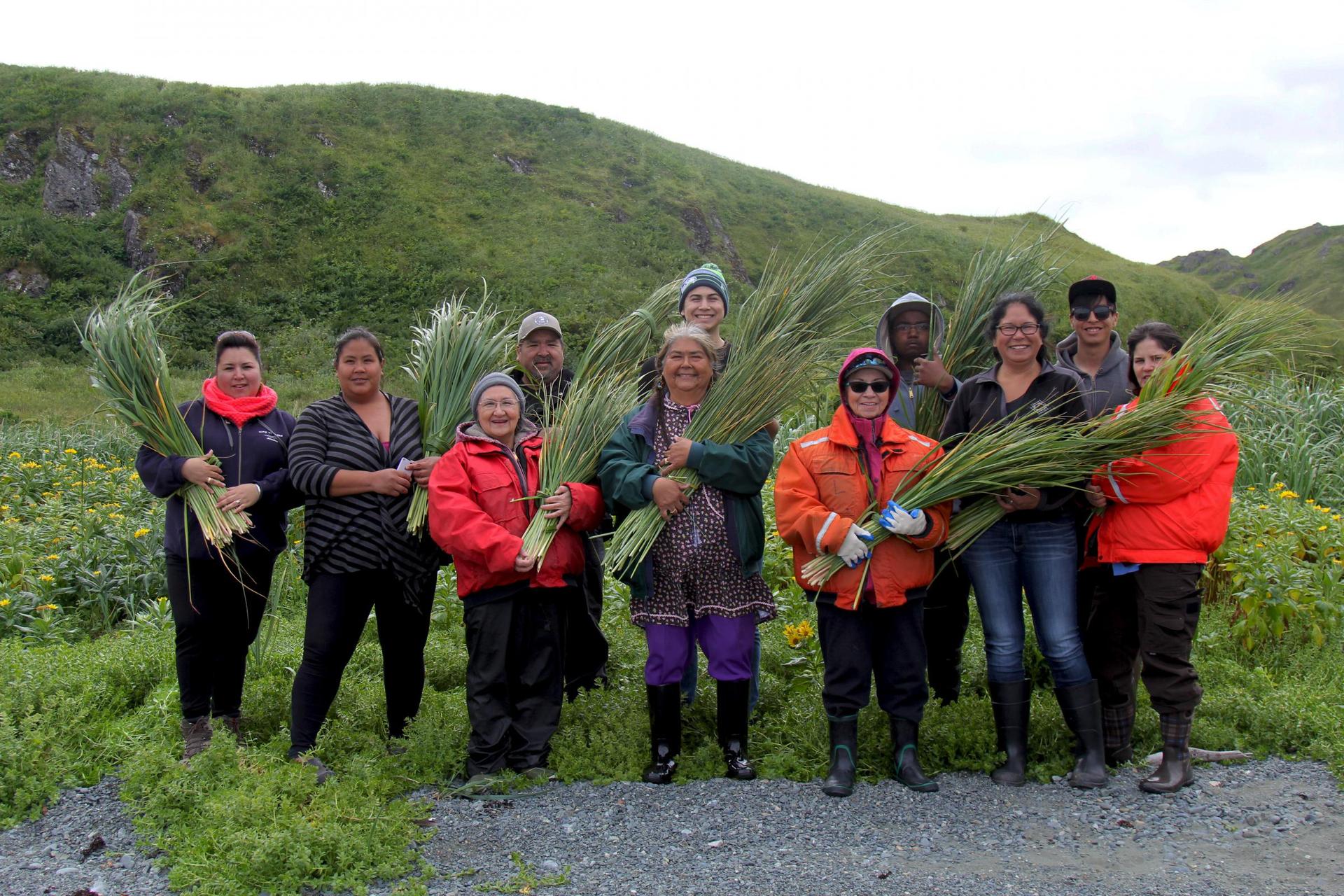 a group of people in a field holding traditional grass baskets