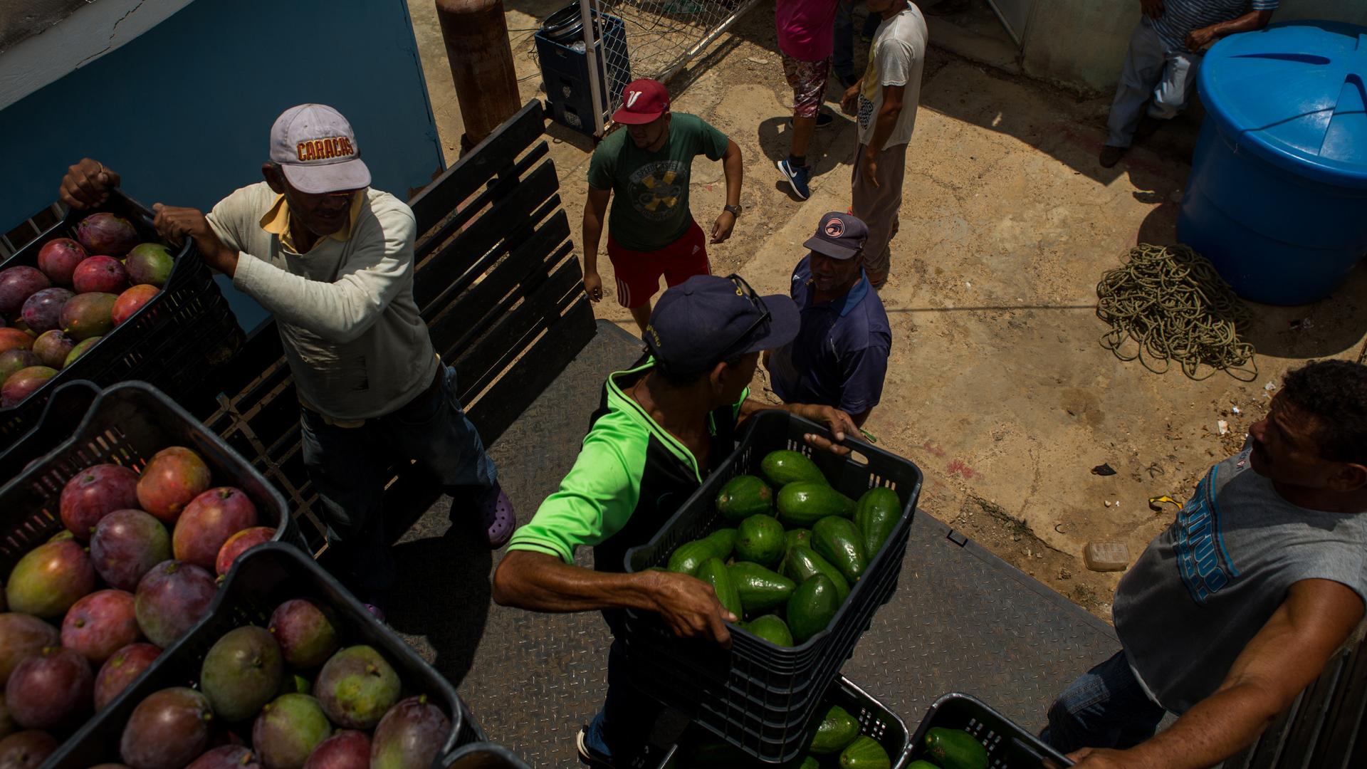 Workers unload produce for sale at a market in Caracas. It's increasingly hazardous work to drive a food delivery truck in Venezuela.