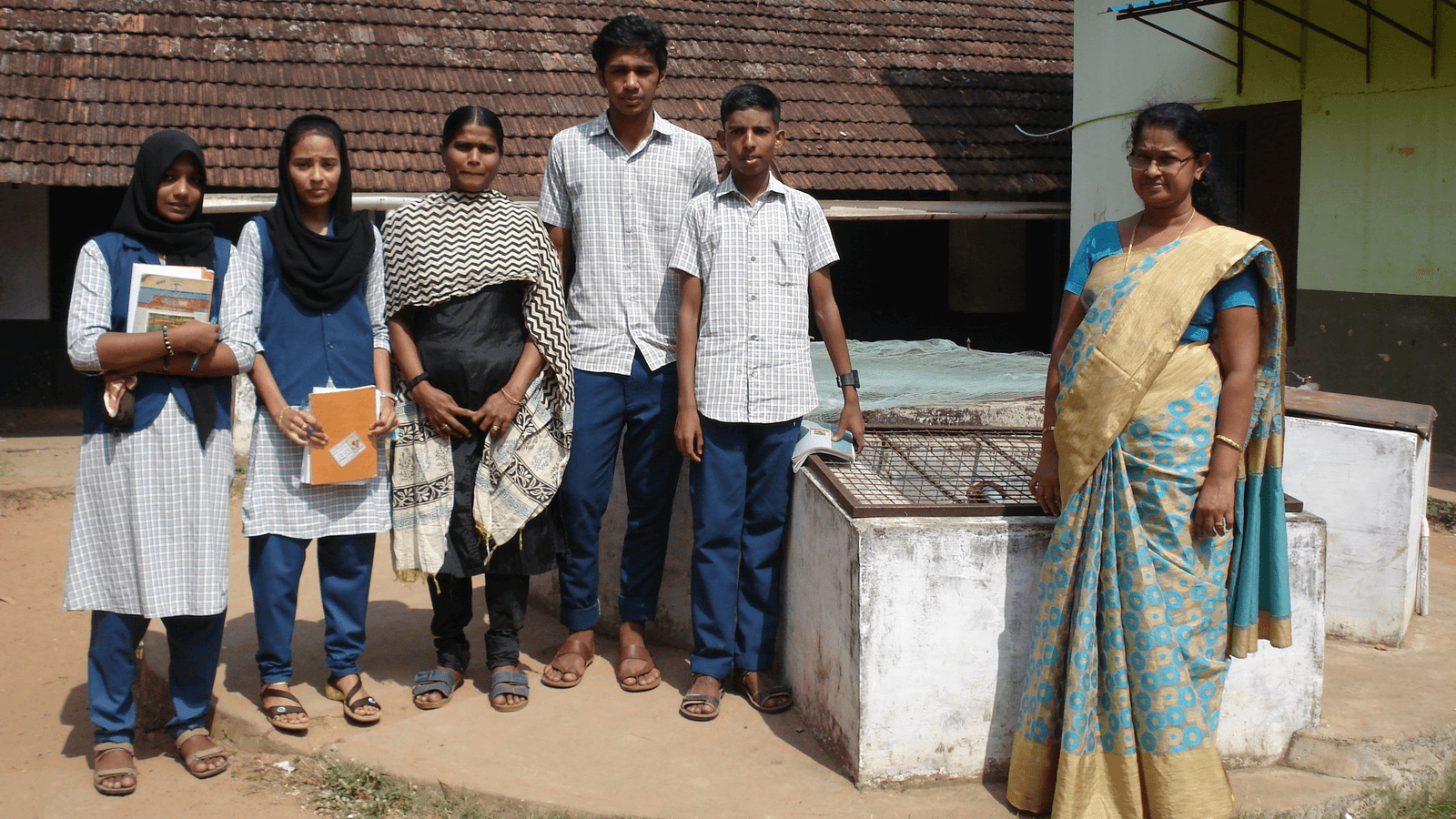 schoolchildren stand near a well at their high school in Kerala, India