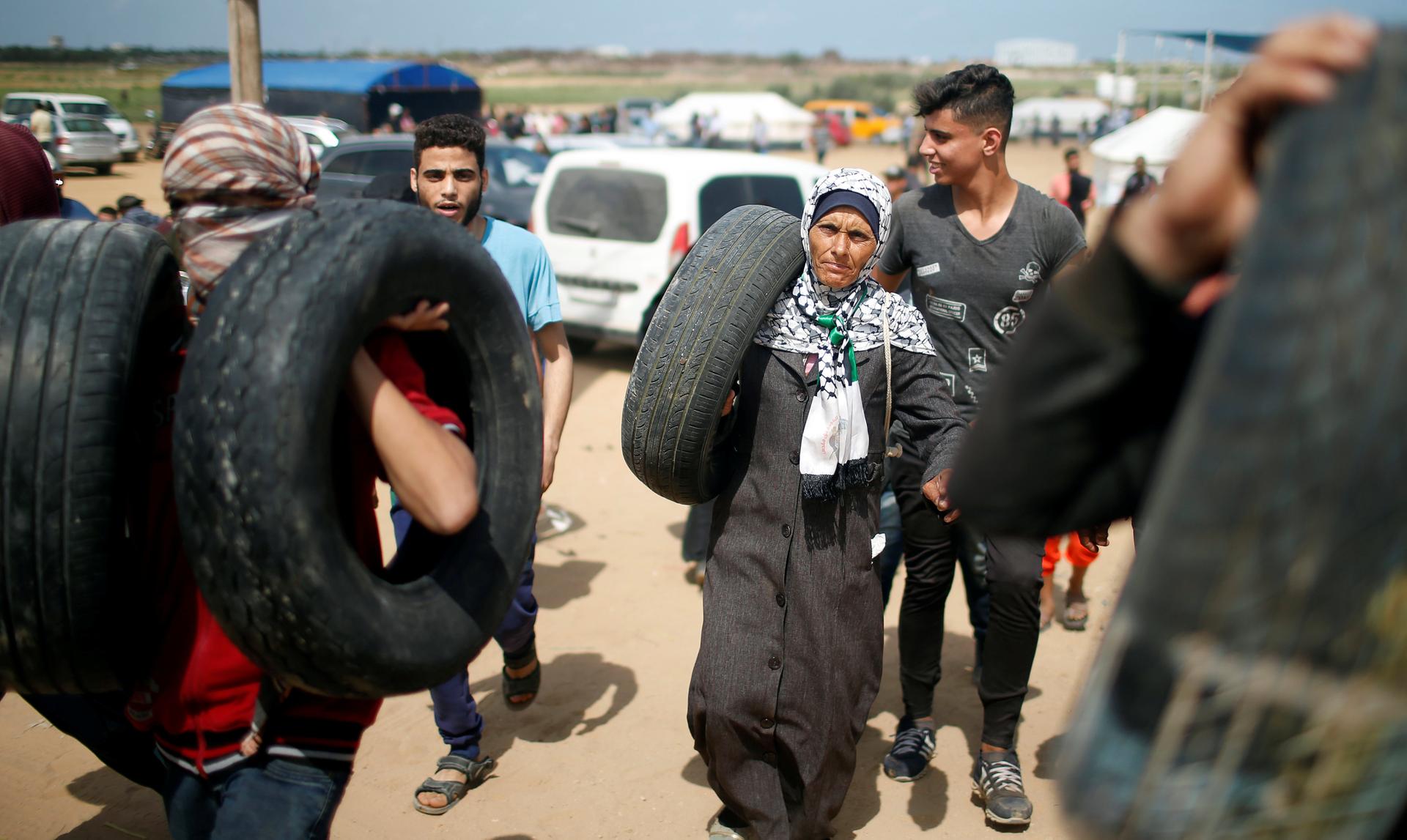 Palestinian demonstrators carry tires during a protest against US embassy move to Jerusalem.