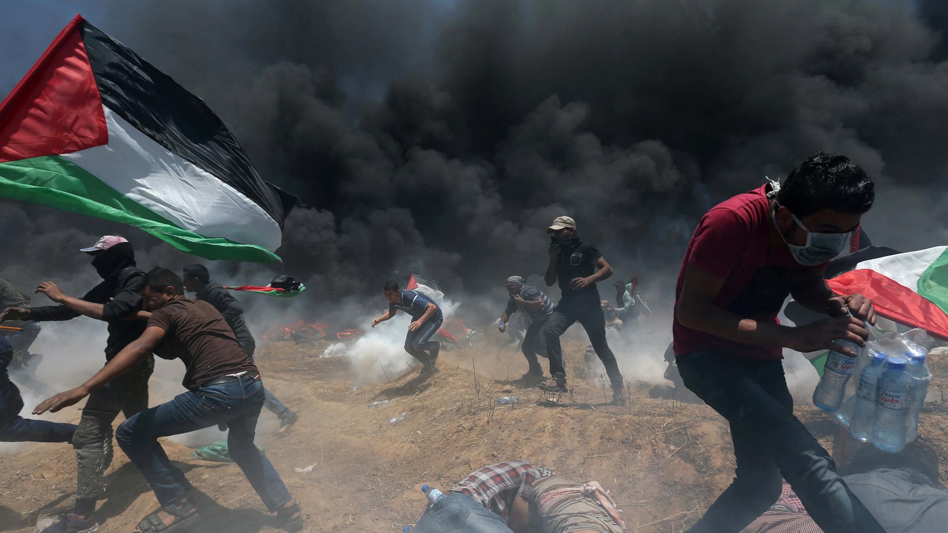 Palestinian demonstrators run for cover from Israeli fire and tear gas during a protest against US embassy move to Jerusalem, May 14, 2018.