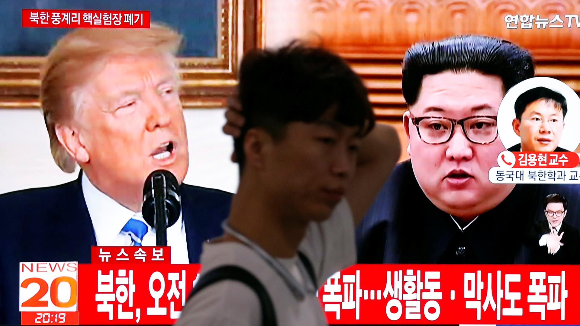 A man walks past a TV showing US President Donald Trump and North Korean leader Kim Jong-un, in Seoul, May 24, 2018.