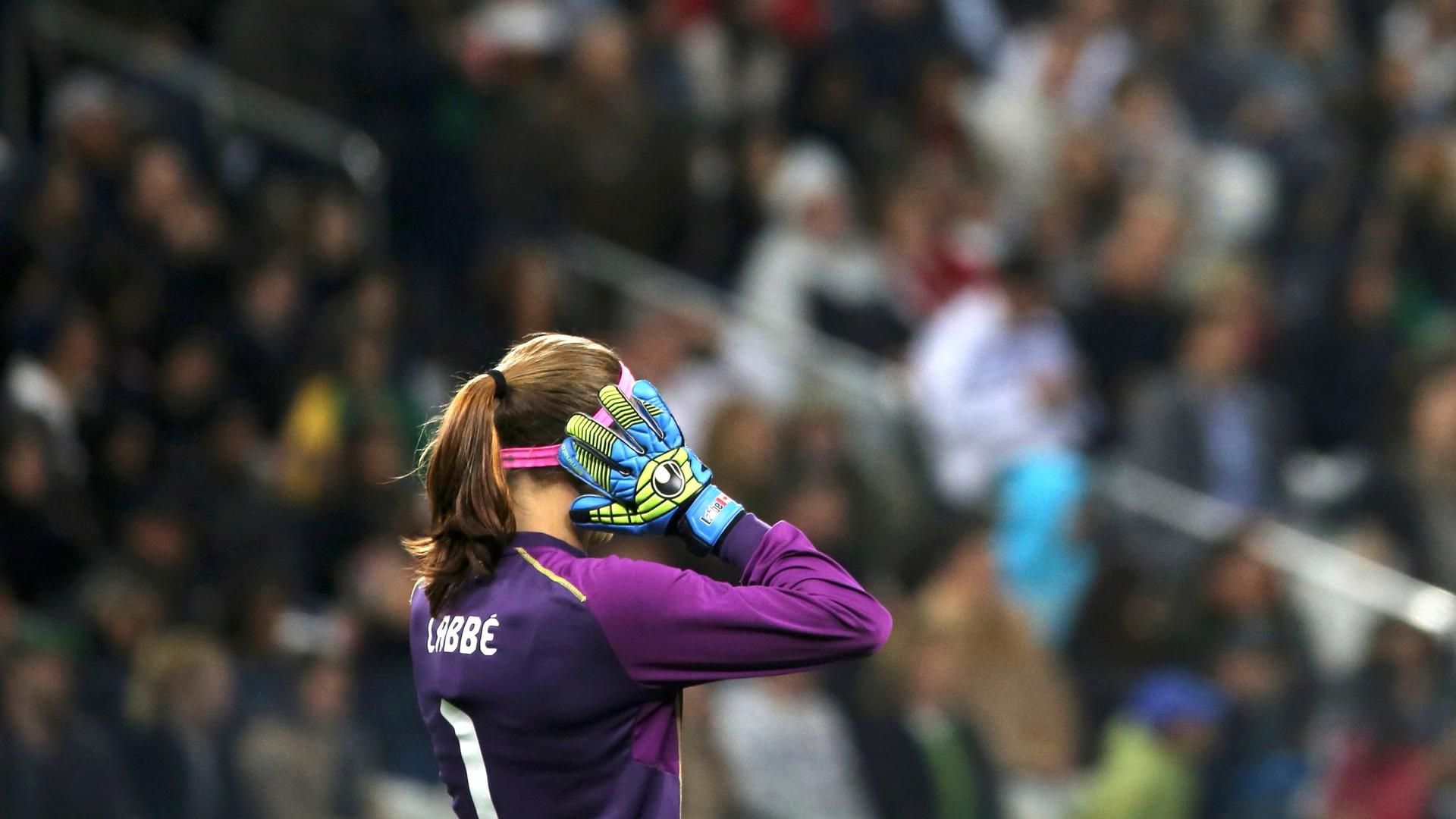 Stephanie Labbe raises her hands while standing in goal.