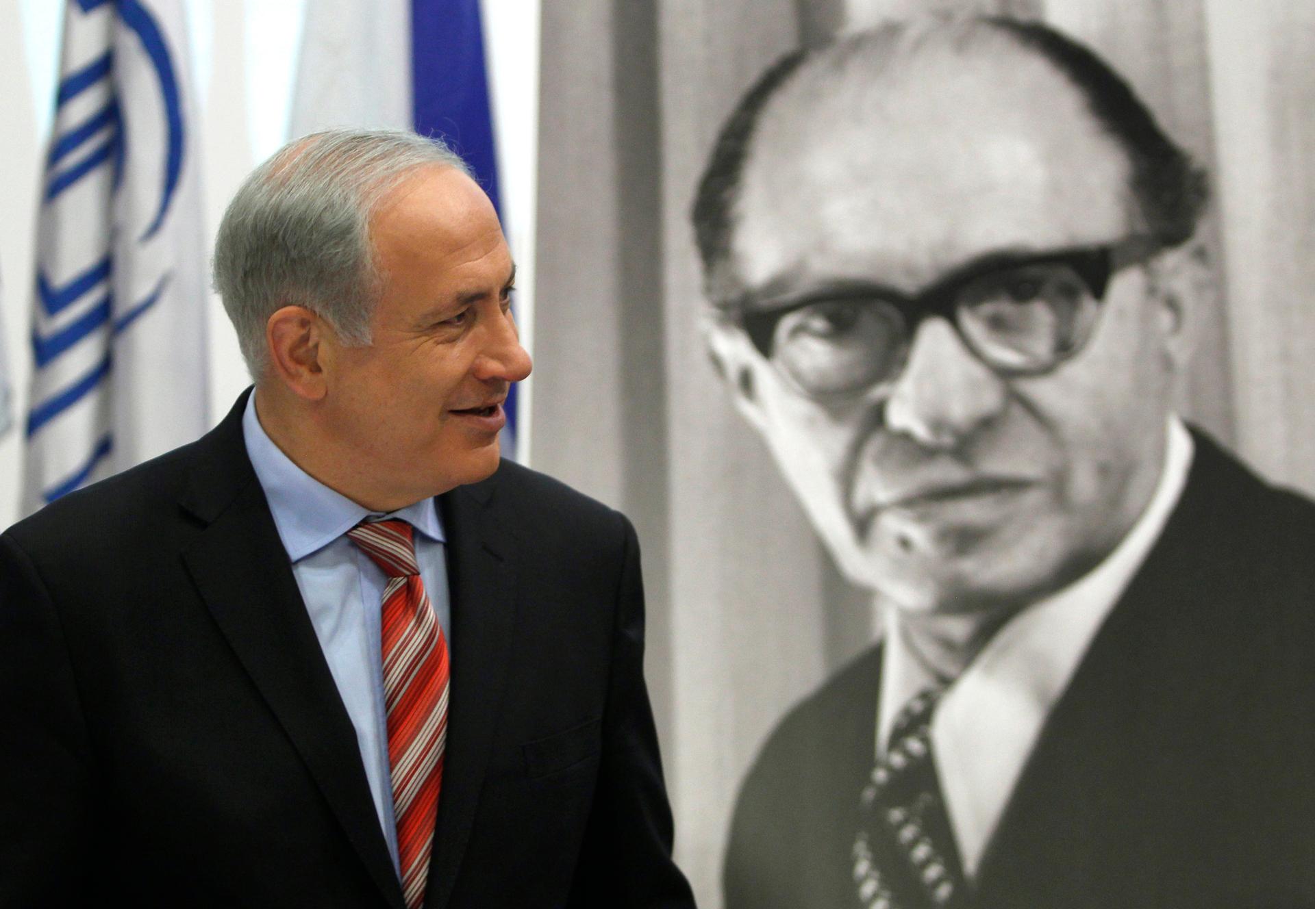 Israel's Prime Minister Benjamin Netanyahu walks in front of a black and white poster